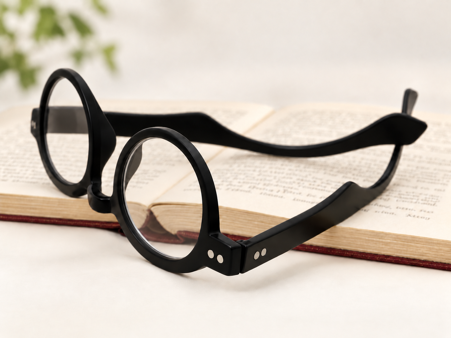 Doctor black rounded reading glasses resting open on the pages of a book