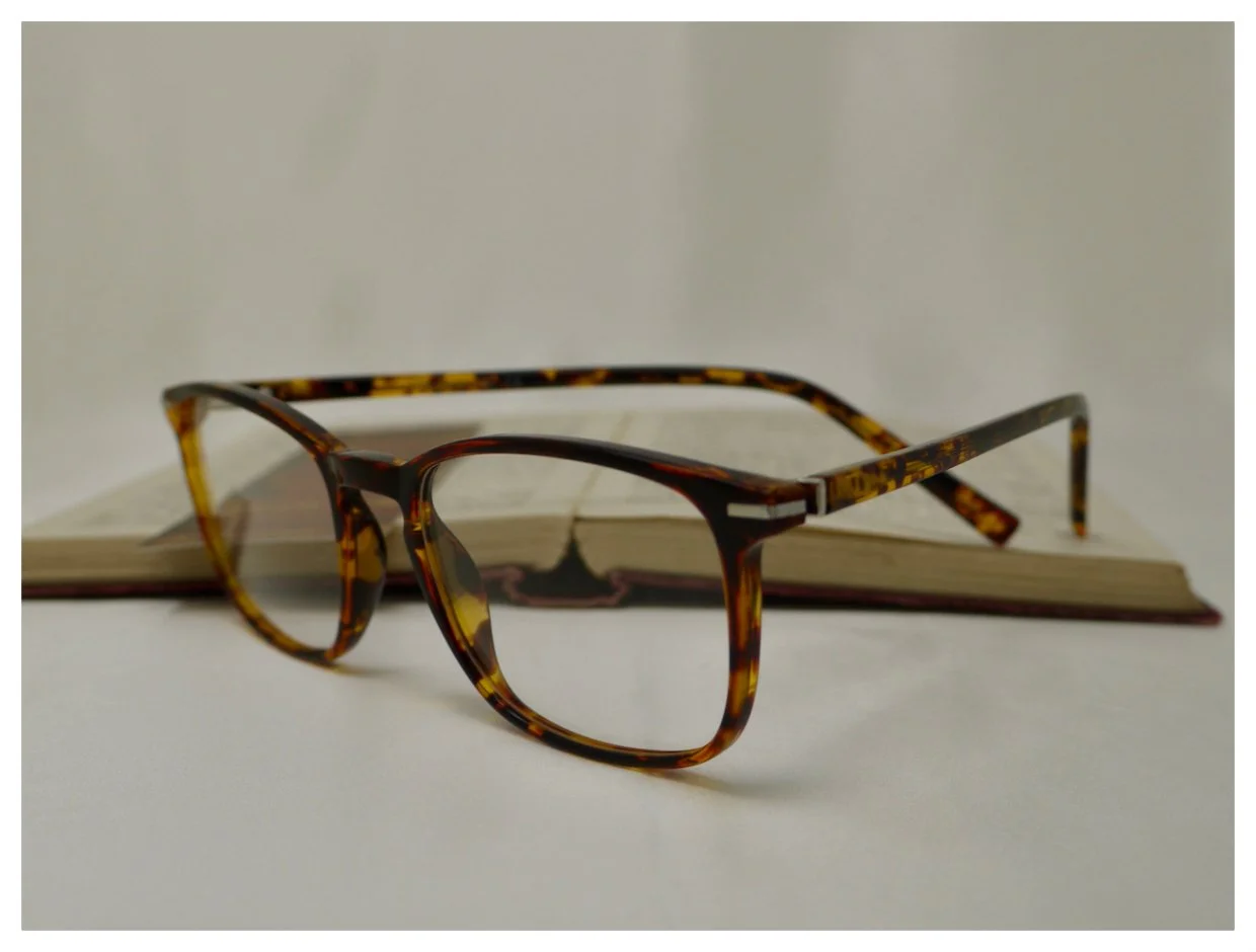 Bespoke tortoiseshell reading glasses resting on an open book