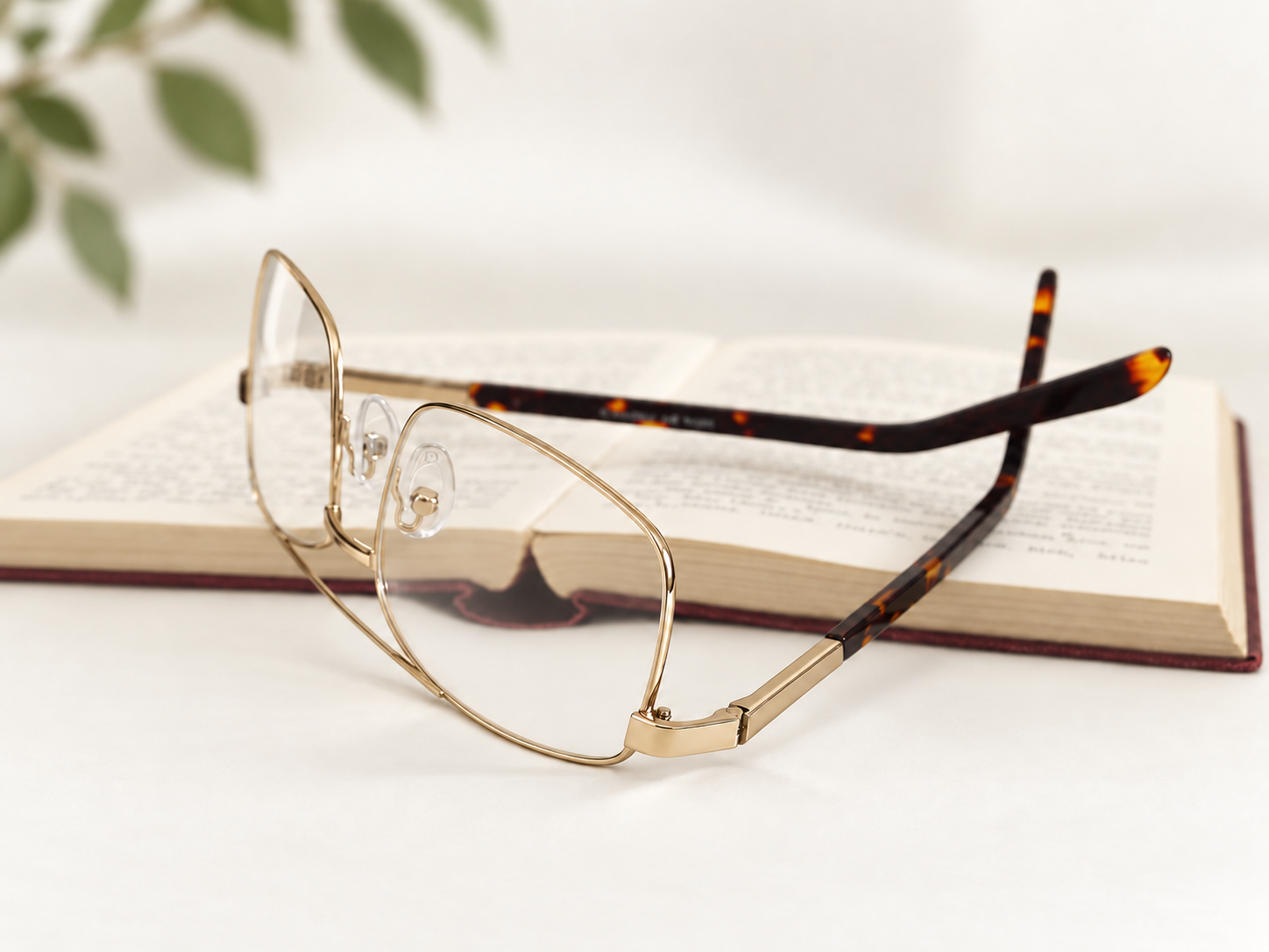 Okia 9 extra-large gold reading glasses beside an open book