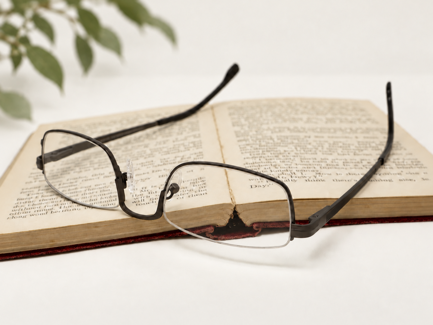 Julian Beaumont 3659 gunmetal reading glasses resting beside an open book