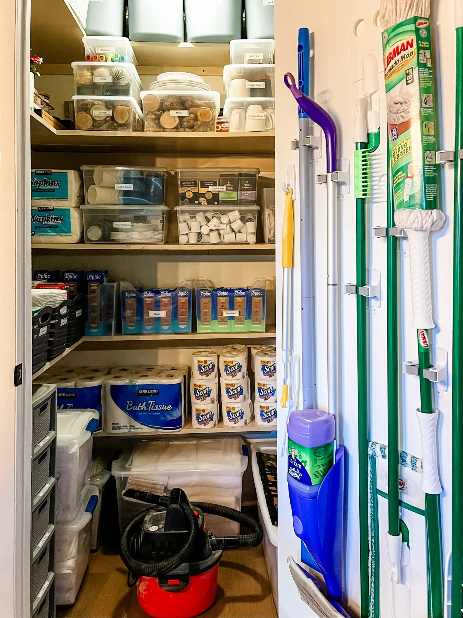 organized storage closet using the back of door to hang brooms and mops using command strip products