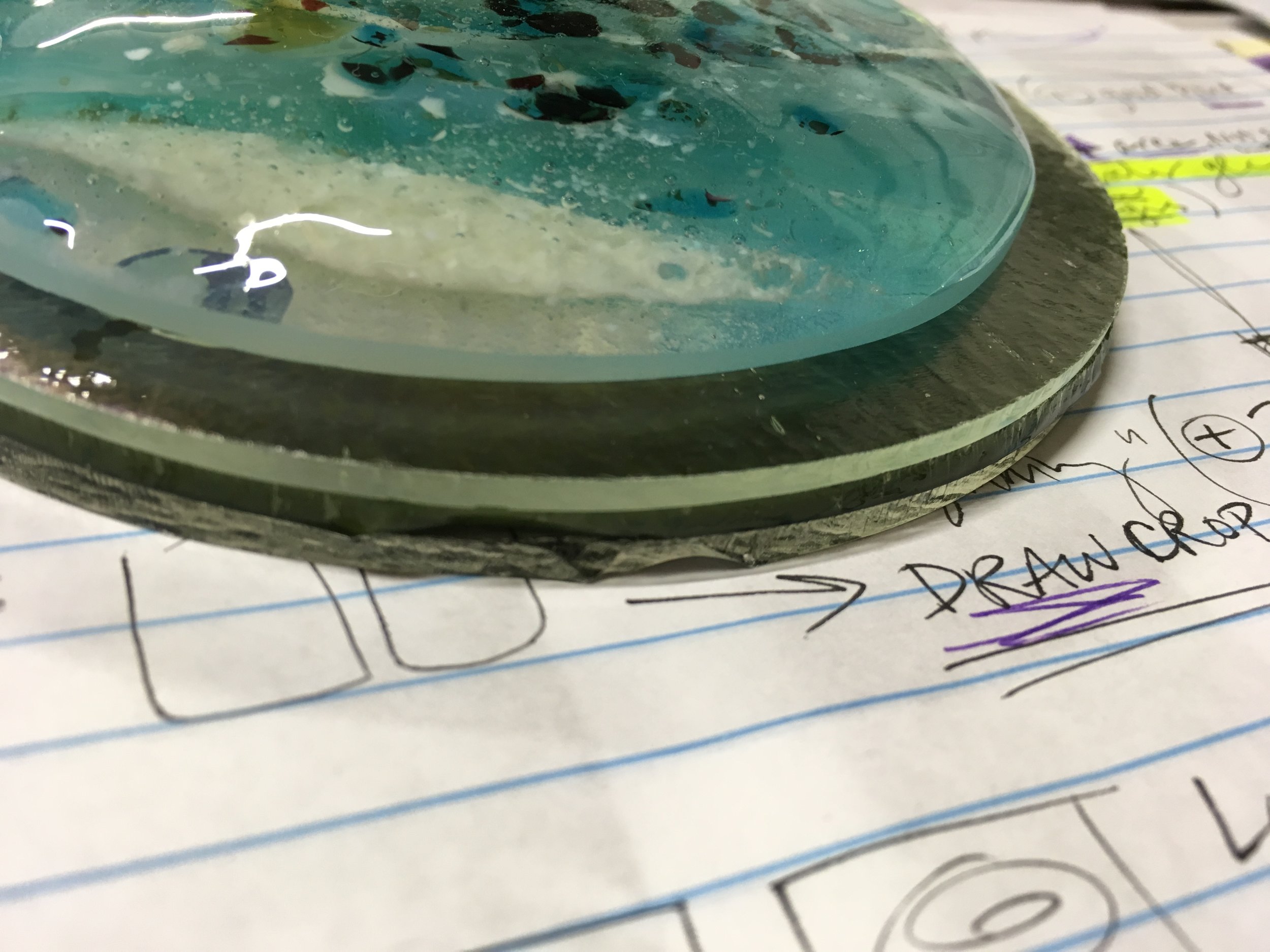 Side view of glass water round layers — bottom 3 are raw sheet glass, and the top has been fired several times already — and edges sanded on belt sander. (I take a lot of notes!)