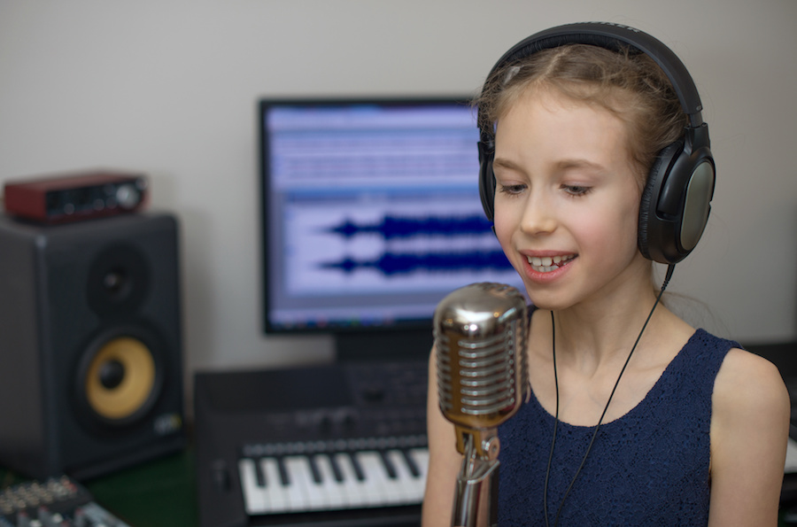 Little girl singing a song in home recording studio.