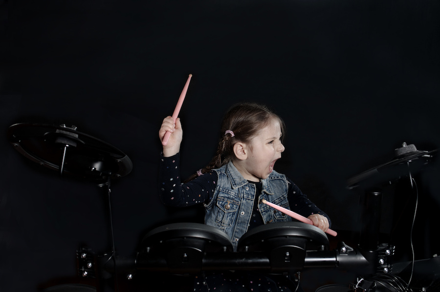 Little caucasian girl drummer play the elettronic drum kit