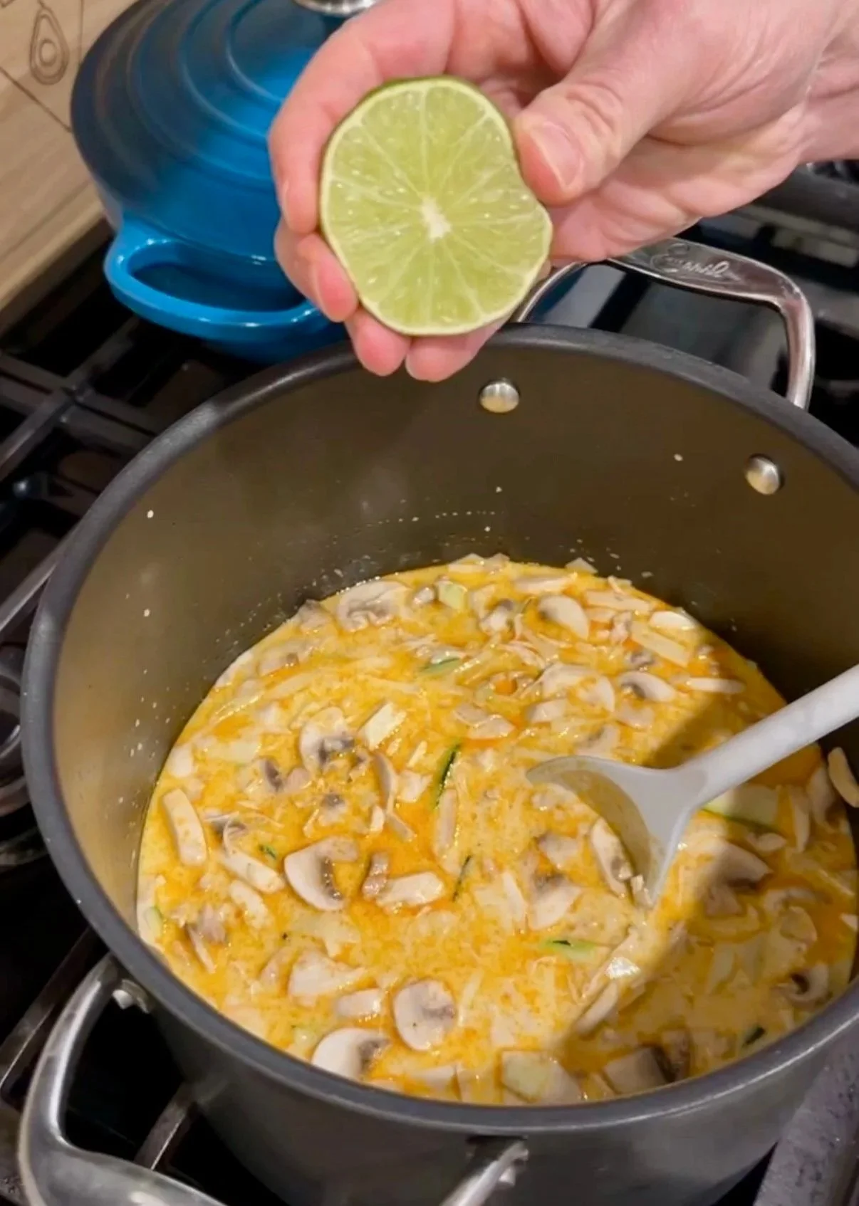 Squeezing lime into a pot of thai chicken soup