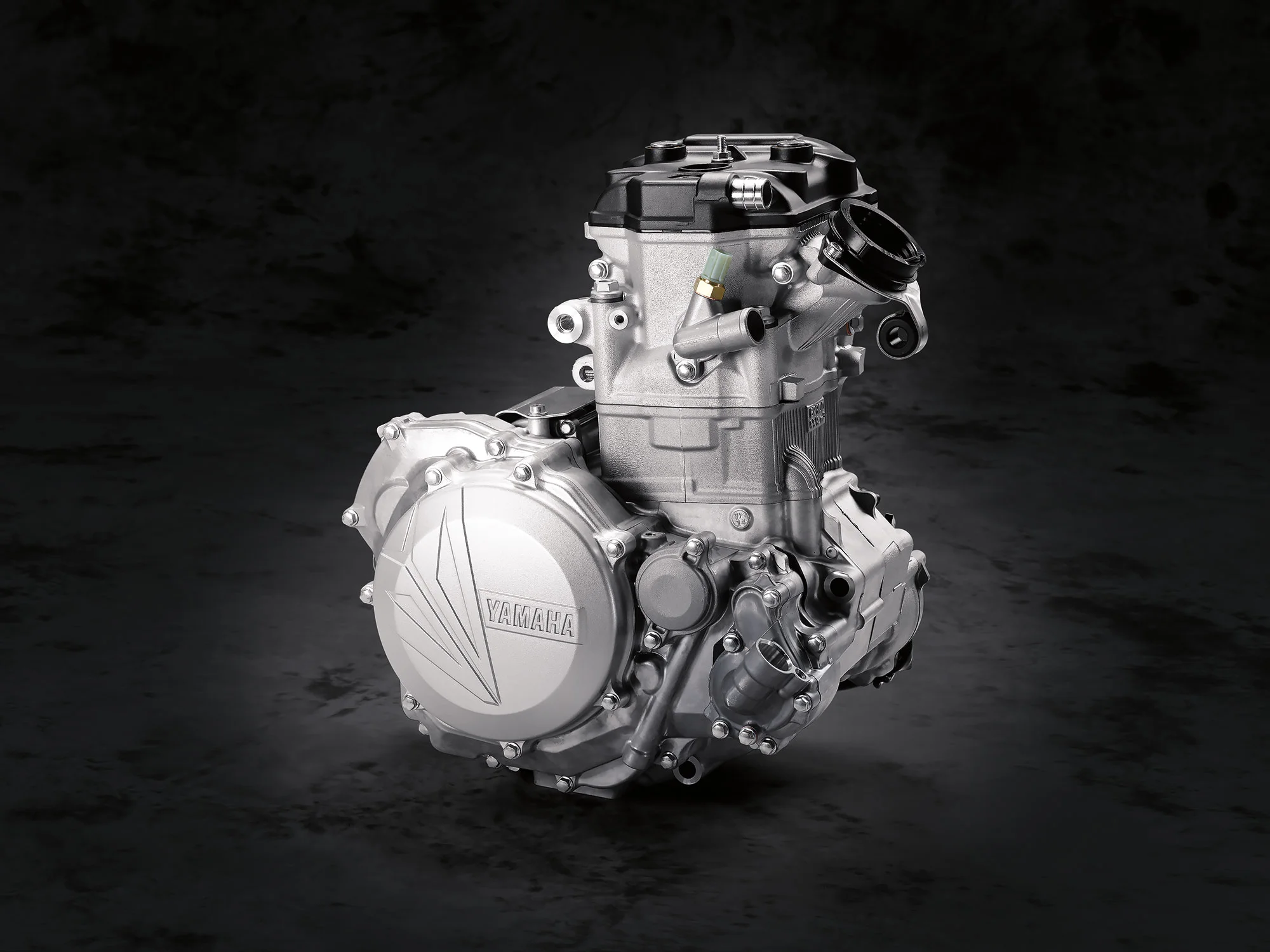 The new angled more upright engine comes with electric start and a whole hosts of other changes: The cylinder head and camshafts have changed with a straighter intake port shape, high lift camshaft profiles, increased valve opening, valve timing overlap is wider, intake camshaft working angle increased and event angle decreased, exhaust camshaft working angle increased, a new Mikuni 44mm throttle body, a change in the piston (lighter and slightly more compression), a piston pin that comes with DLC coating, a revised ECU setting, a longer electrode on the spark plug along with a spark plug cap holder, stronger 2nd and 3rd gears in the transmission, pressure plate shape change in the clutch, steel cutch plate surface grinding is added and improved shape of clutch spring has been changed. 