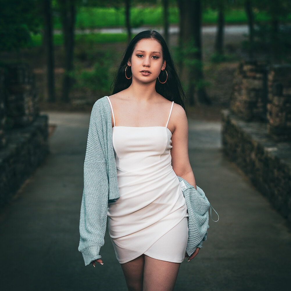 high school senior wearing a white dress and cardigan walks across a bridge during her senior pictures session with Don Evans Photography in Greensboro NC.jpg