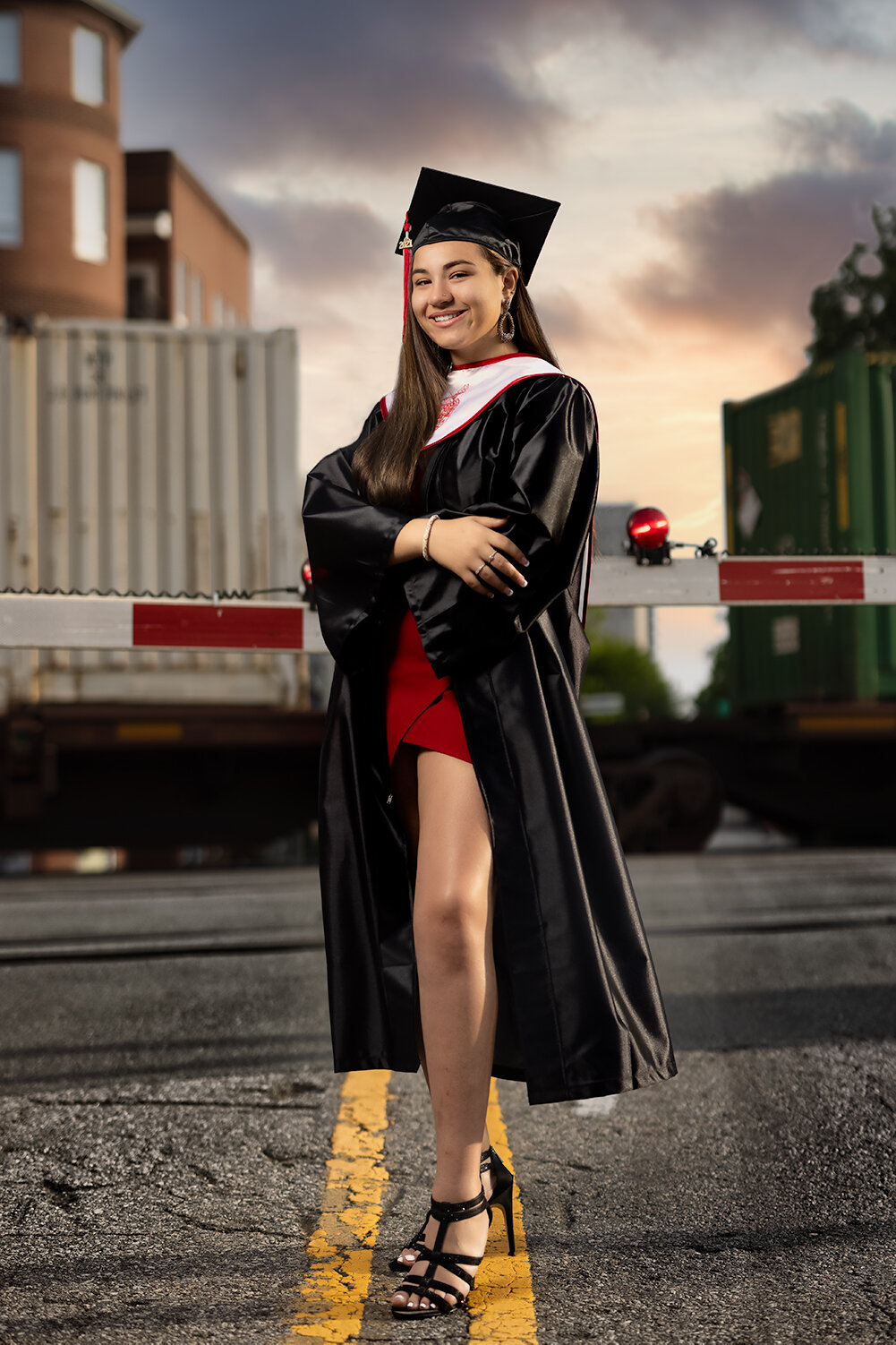 high school senior poses in her graduation cap and gown in front of train tracks and active train for Don Evans Photography in Greensboro NC.jpg