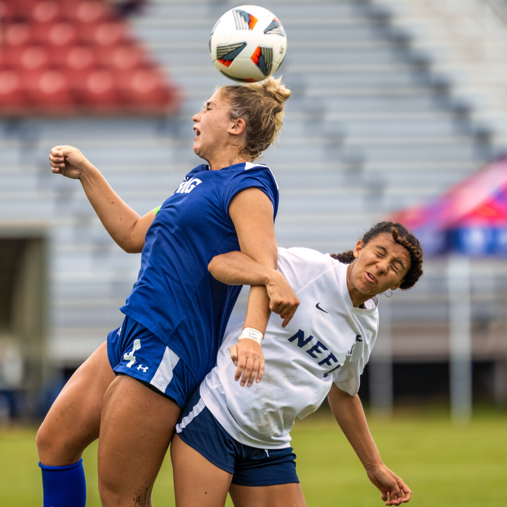  girls academy league NEFC soccer player locks arms with an IMG player during a header while playing in a national tournament in Bryan Park Soccer Complex taken by Don Evans Photography in Greensboro NC 