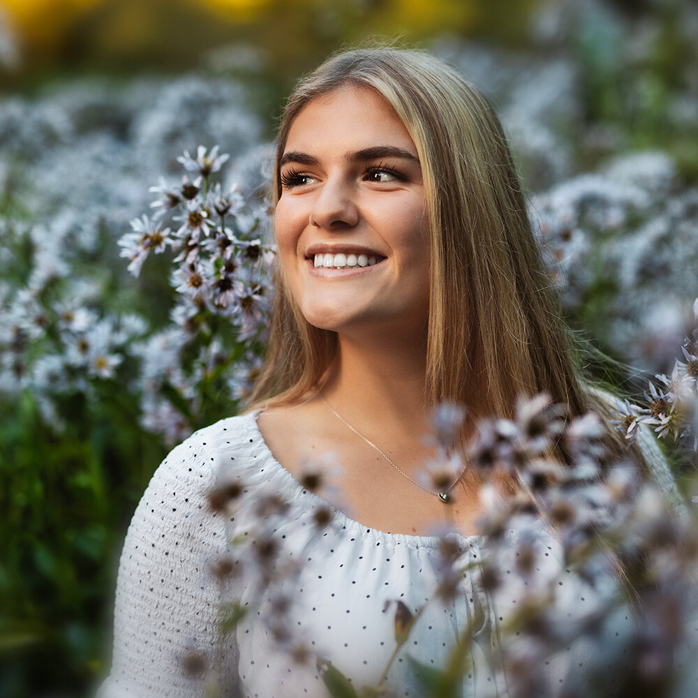 Don Evans Photography in Greensboro high school senior stands in tall flowers while posing during her senior picture photo session.jpg