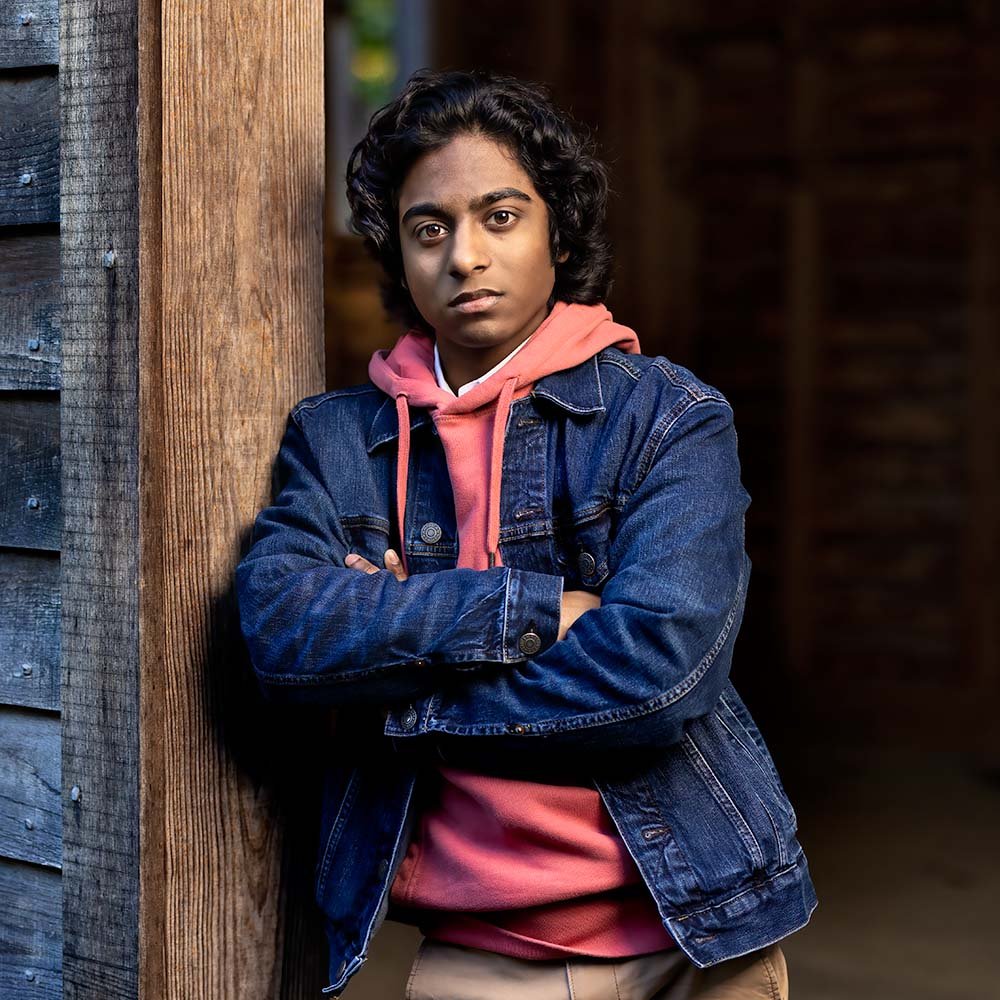 Don Evans Photography in Greensboro high school senior wearing a blue jean jacket and hoodie leans against a cabin wall wall posing for his senior picture photo session.jpg