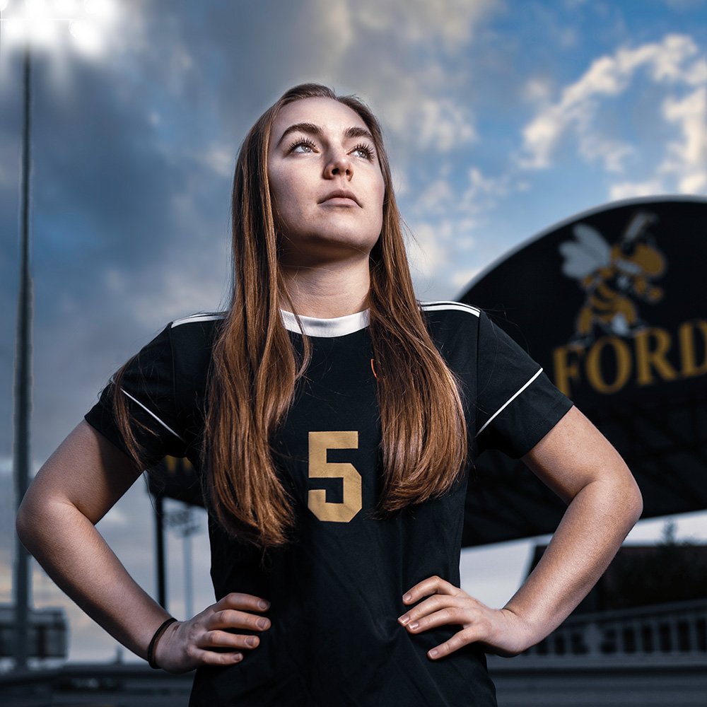 Don Evans Sports Photography in Greensboro NC high school senior soccer player stands with hands on hips looking across the field during her senior picture photo session