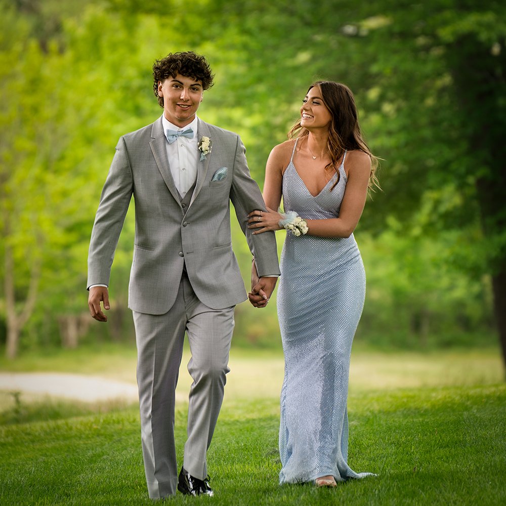 Don Evans Photography in Greensboro high school seniors dressed for prom walking through the grass during their senior picture photo session