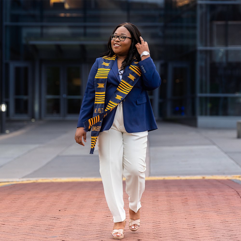Don Evans Photography in Greensboro NC A&amp;T college grad wearing university colors while walking on campus during her graduation senior picture photo session
