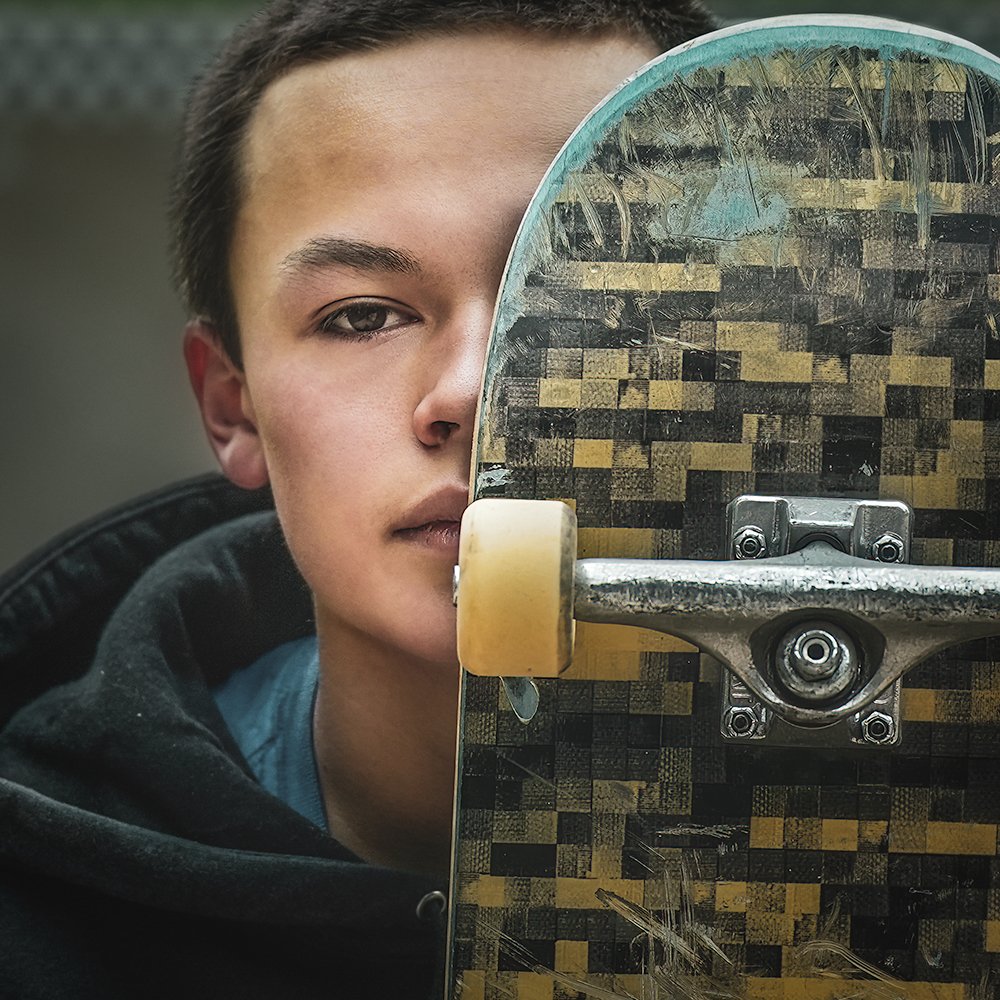 Don Evans Photography in Greensboro high school senior holds his skateboard to his face during his senior picture photo session