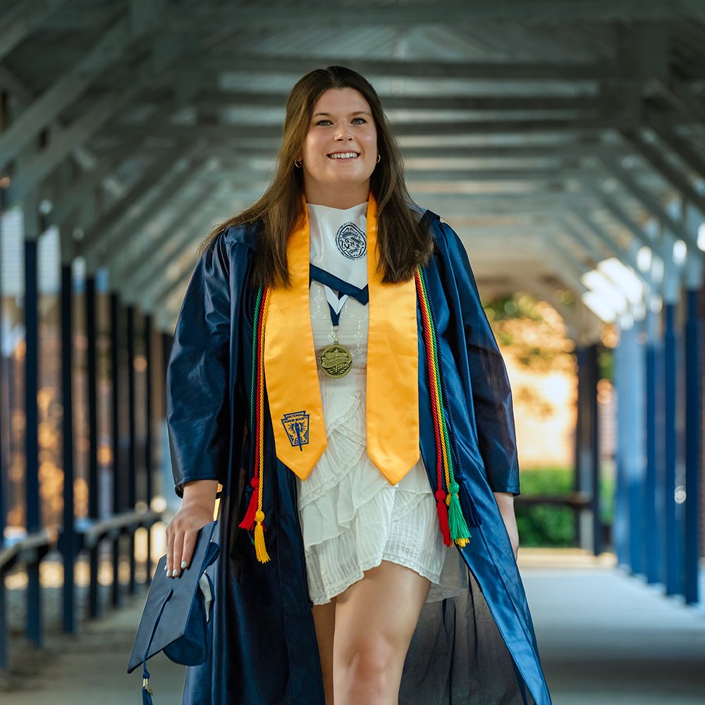 Don Evans Photography in Greensboro high school senior wearing her blue cap and gown walking on campus during her graduation senior picture photo session