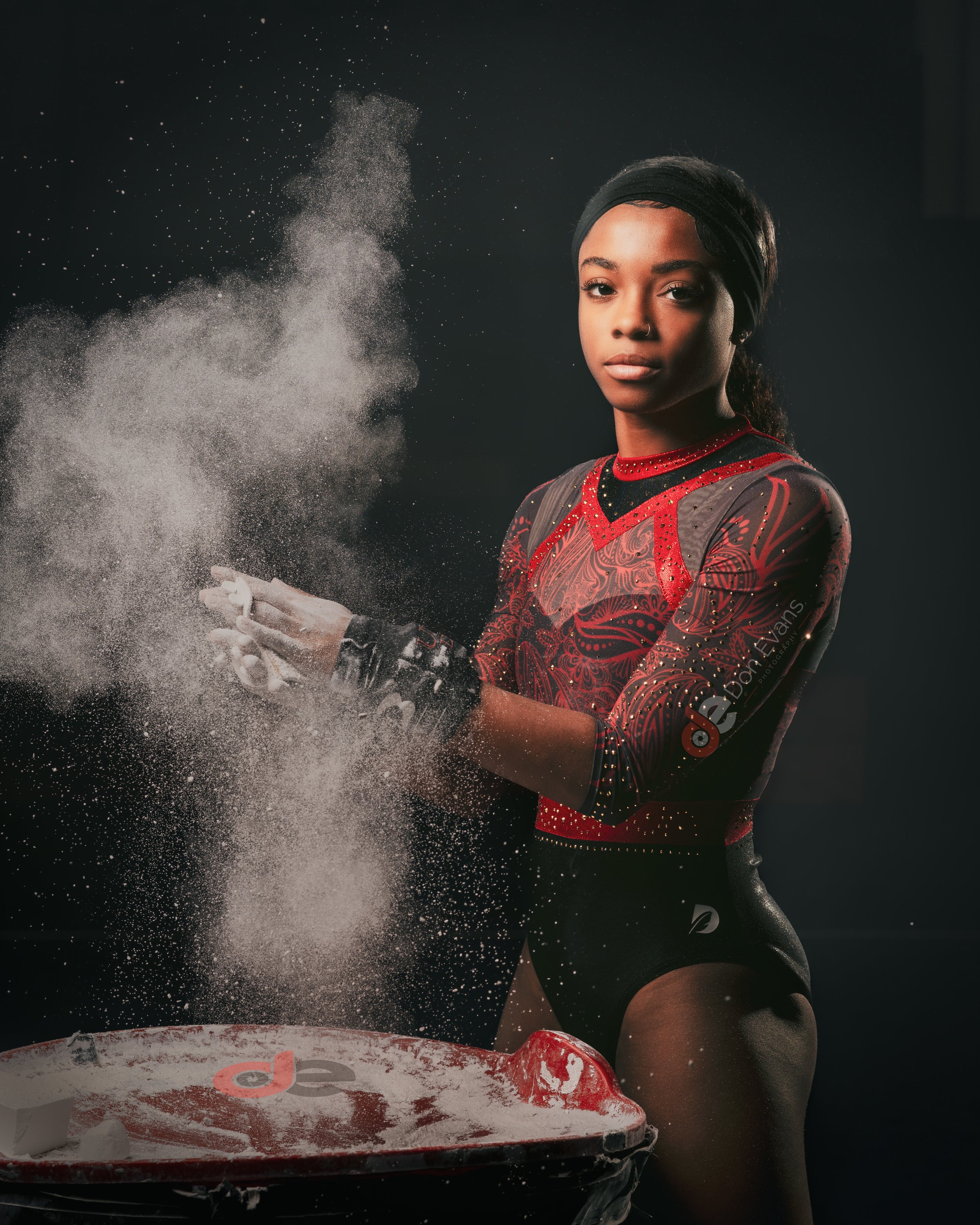 Don Evans Sports Photography in Greensboro NC Gymnast chalks before the bars during her gymnastics tournament competition with dramatic lighting 