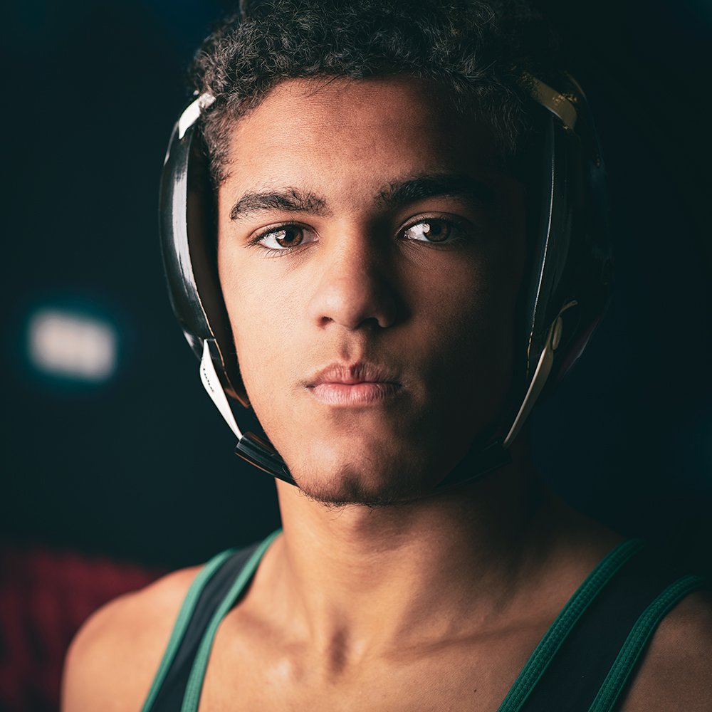 Don Evans Sports Photography in Greensboro NC Dramatic Senior Sports Portraits of a wrestler wearing headgear stares at the camera during his senior banner photo session.jpg