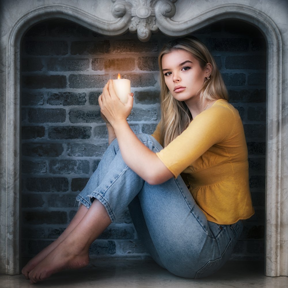 Don Evans Photography in Greensboro college student sitting in a fireplace and holding a candle during her model photo session.jpg