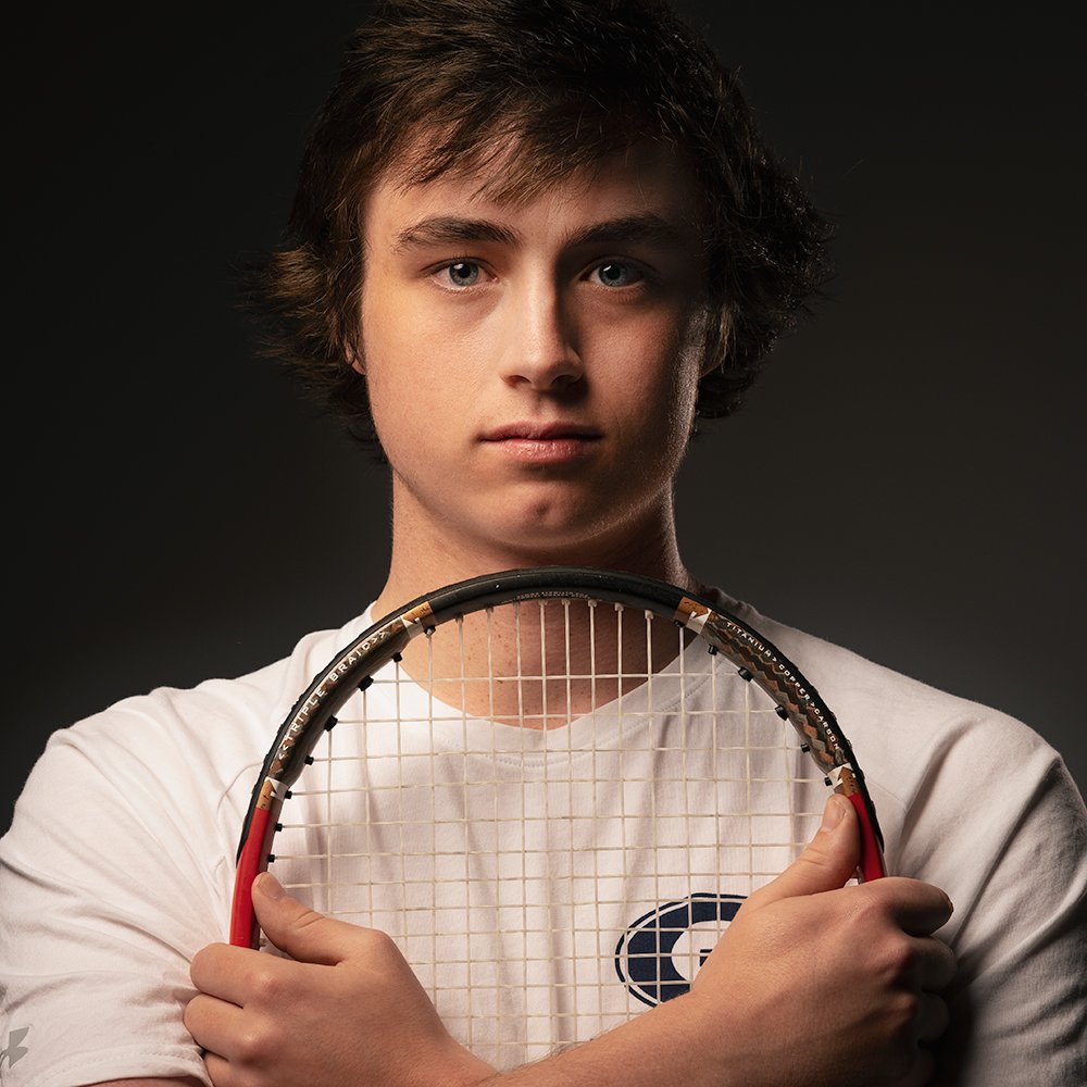 Don Evans Photography in Greensboro picture of a mens tennis player holding his racket in front and looking at the camera during a senior pictures photo session