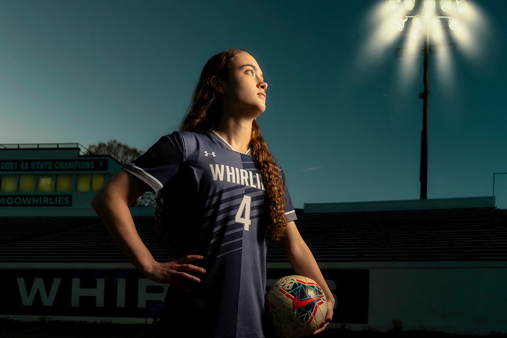  Don Evans Sports Photography in Greensboro NC high school senior soccer player stands in a stadium with a ball during her senior sports portrait and banner photo session.jpg 
