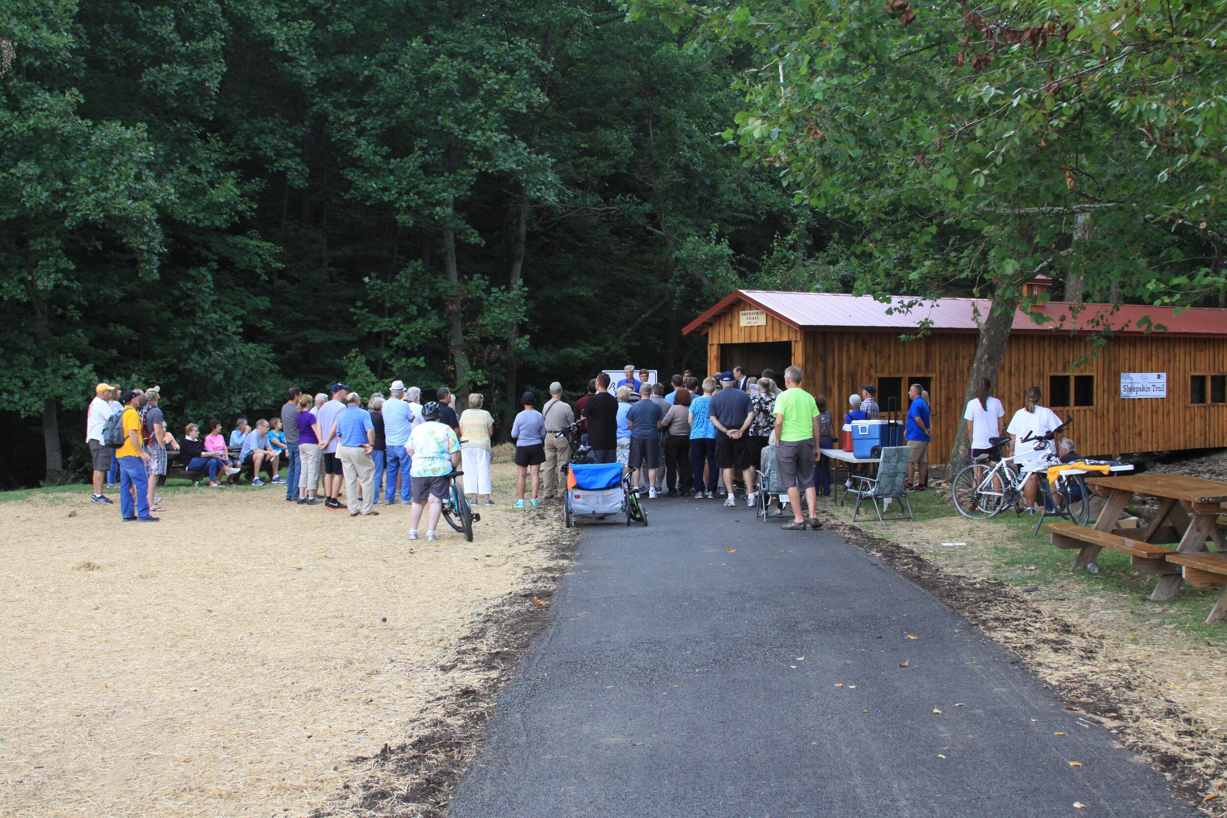 A large group of trail enthusiasts gather at the Hutchinson Park covered bridge