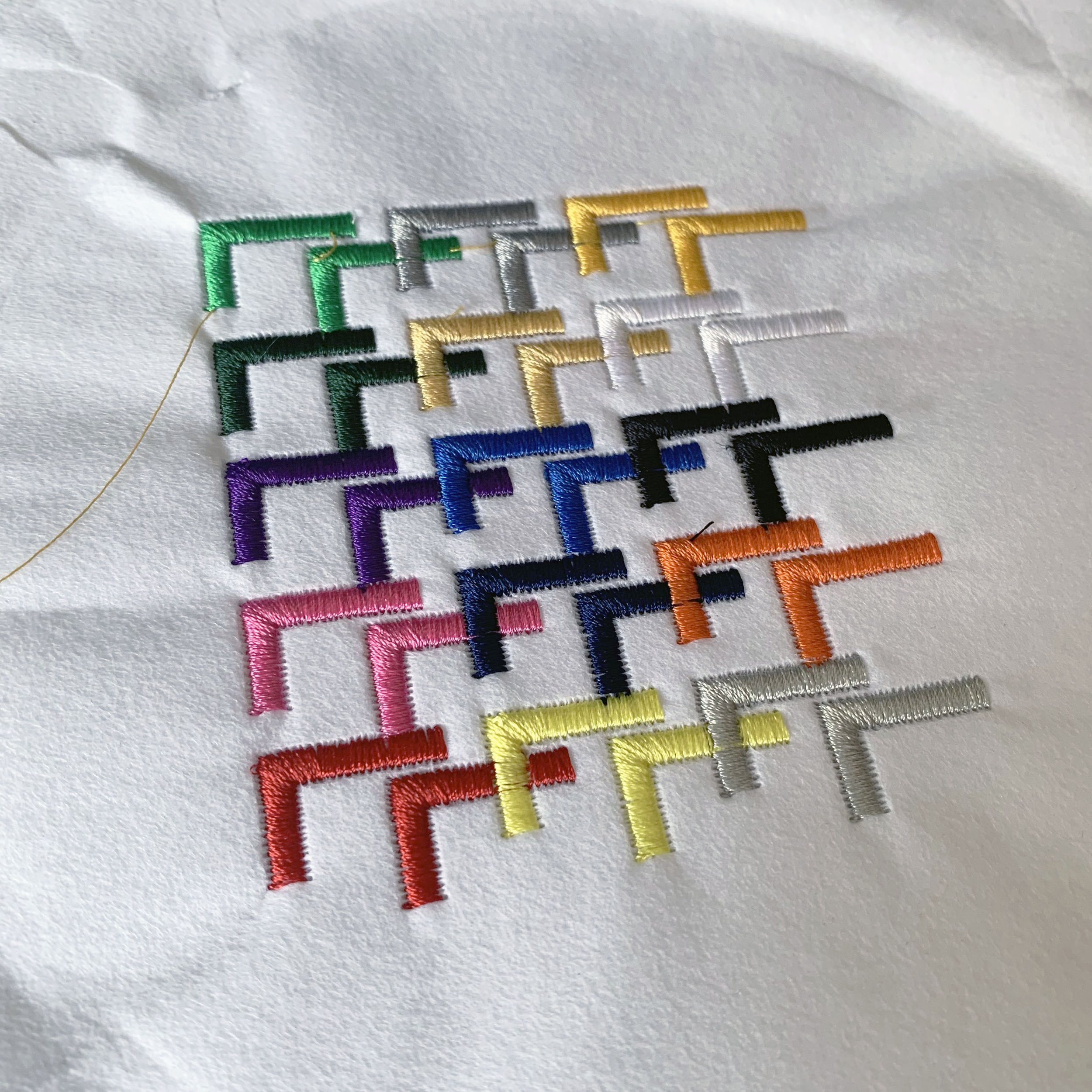 Embroidered Logo: an array of overlapping right angle brackets of varying colors