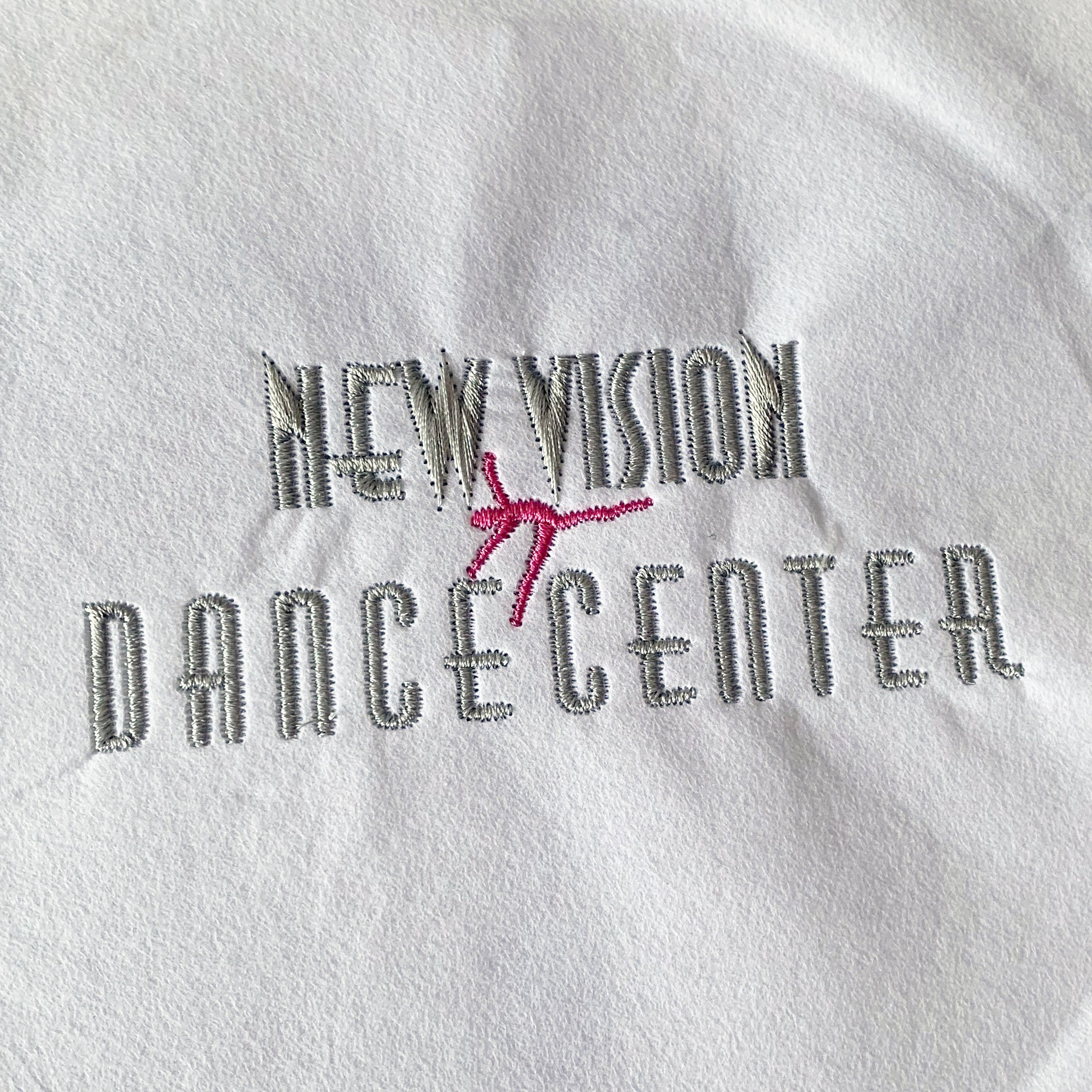 Embroidered Logo: a simple logo with the words 'New Vision Dance Center' and a dancing pink figure