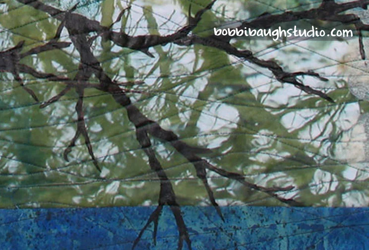 The watery reflections at the lower right came from a photo I took of a pond in Georgia. I did almost nothing to the transfer after getting it on the fabric. The picture came out clearly and I love the sense of mixed reality – trees, but upside down, and rippling, as reflected in the water.