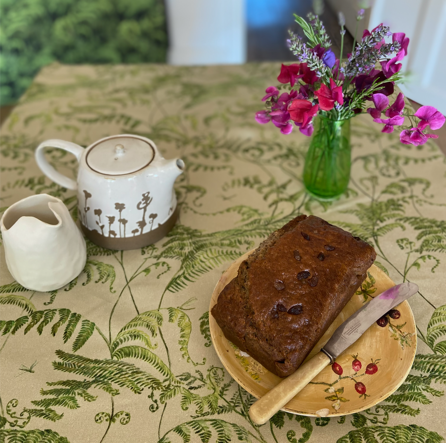 botanical fern table cloth laid with tea, cake and sweet pea flowers