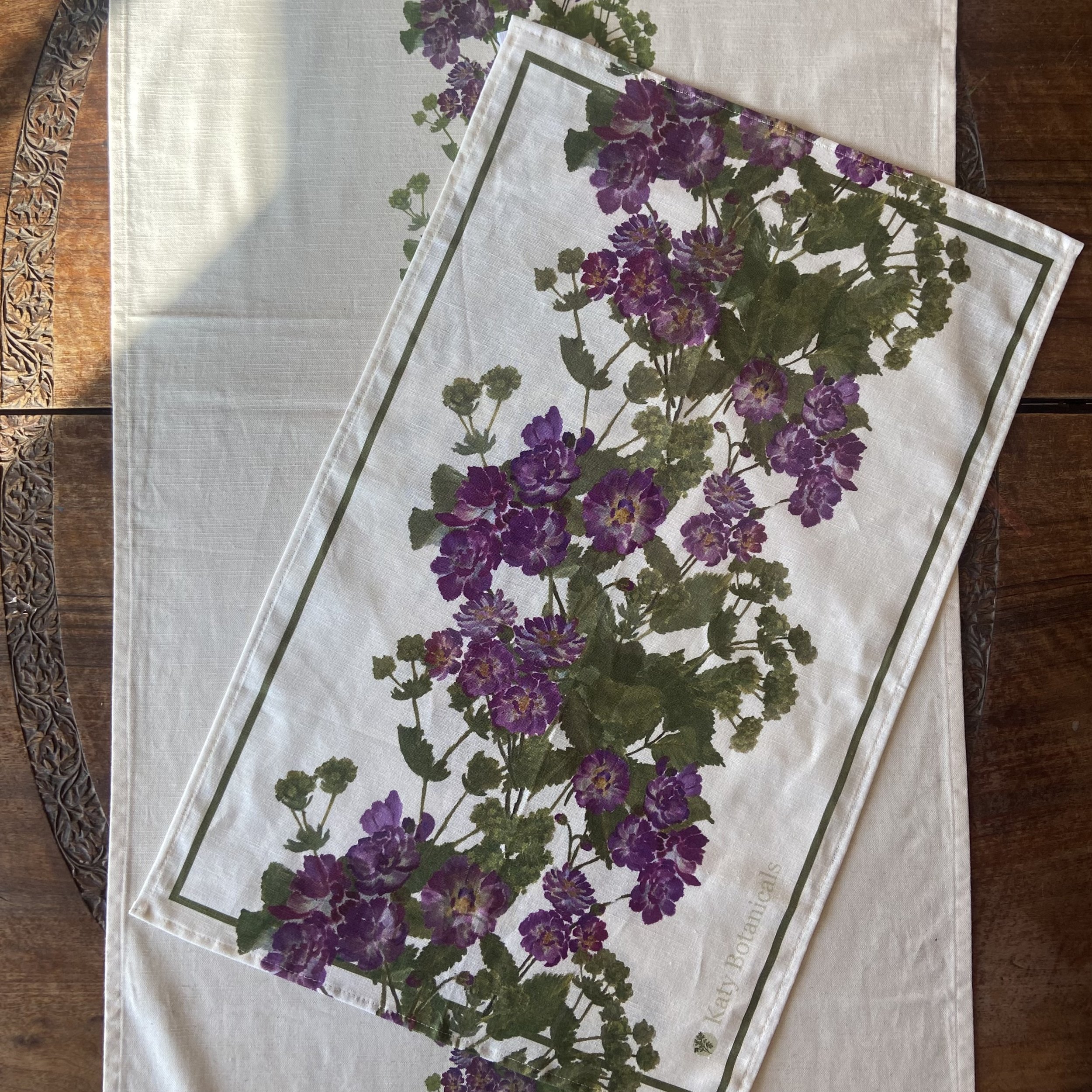 white linen tea towel and table runner displaying hand painted spring roses design