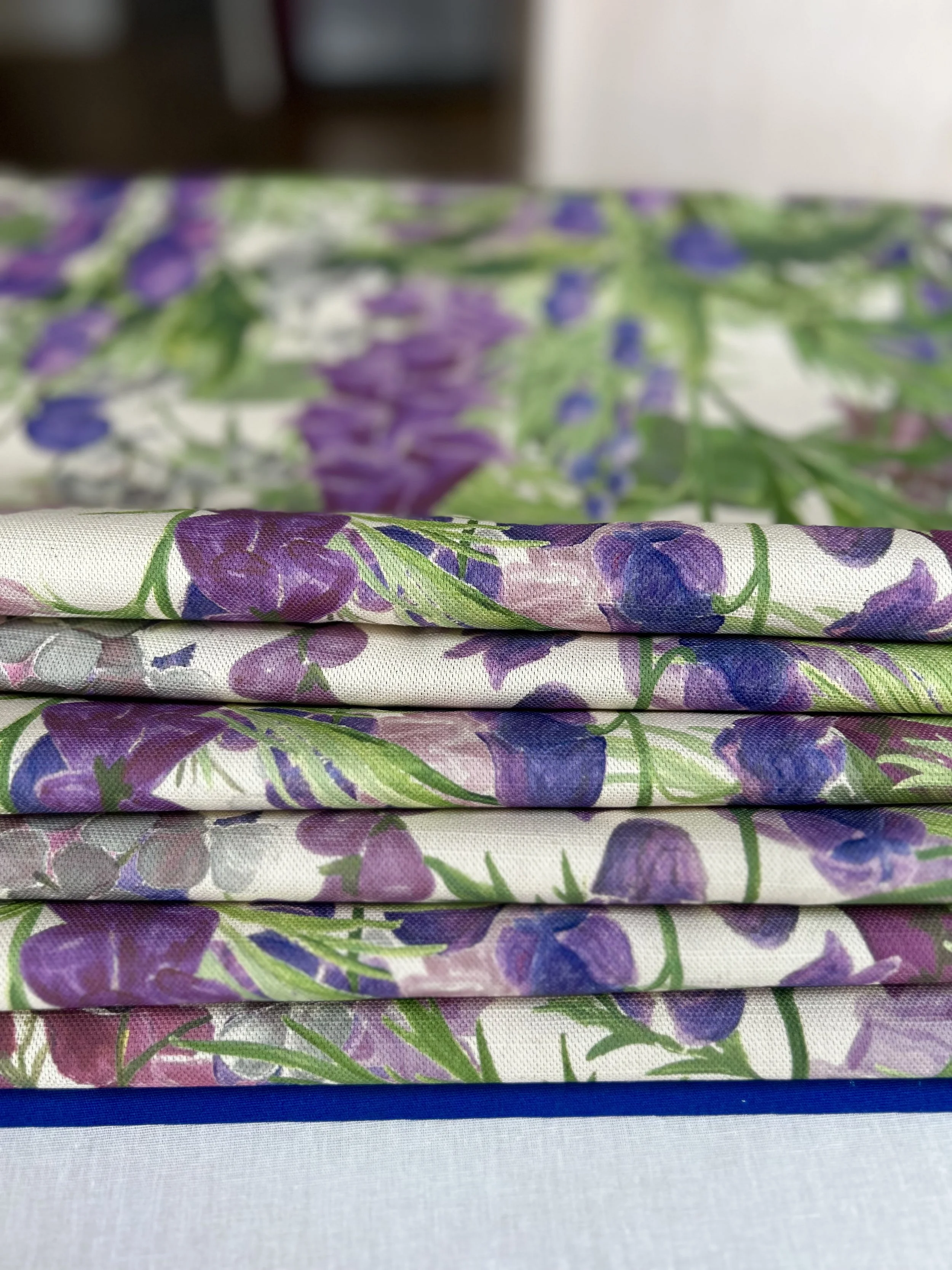 A pile of folded floral linen featuring foxgloves and designed by Katy Botanicals, printed in the UK