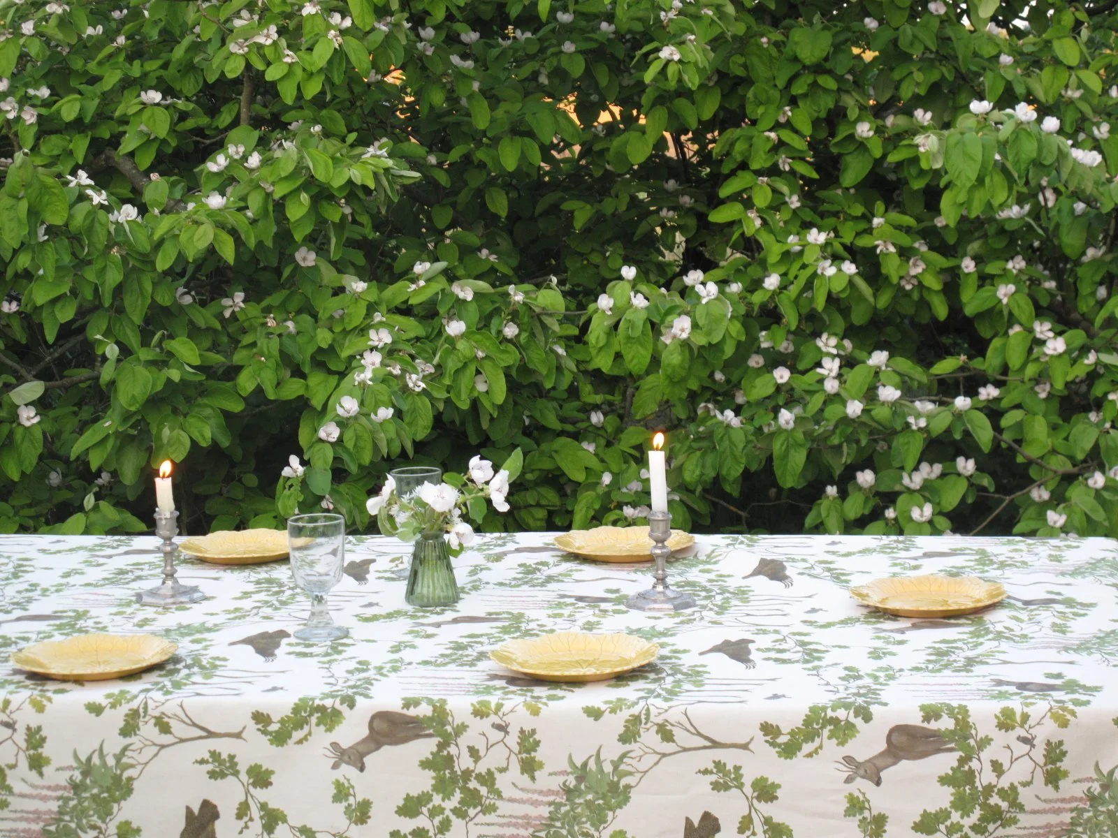 Woodland design linen tablecloth against a flowering quince tree