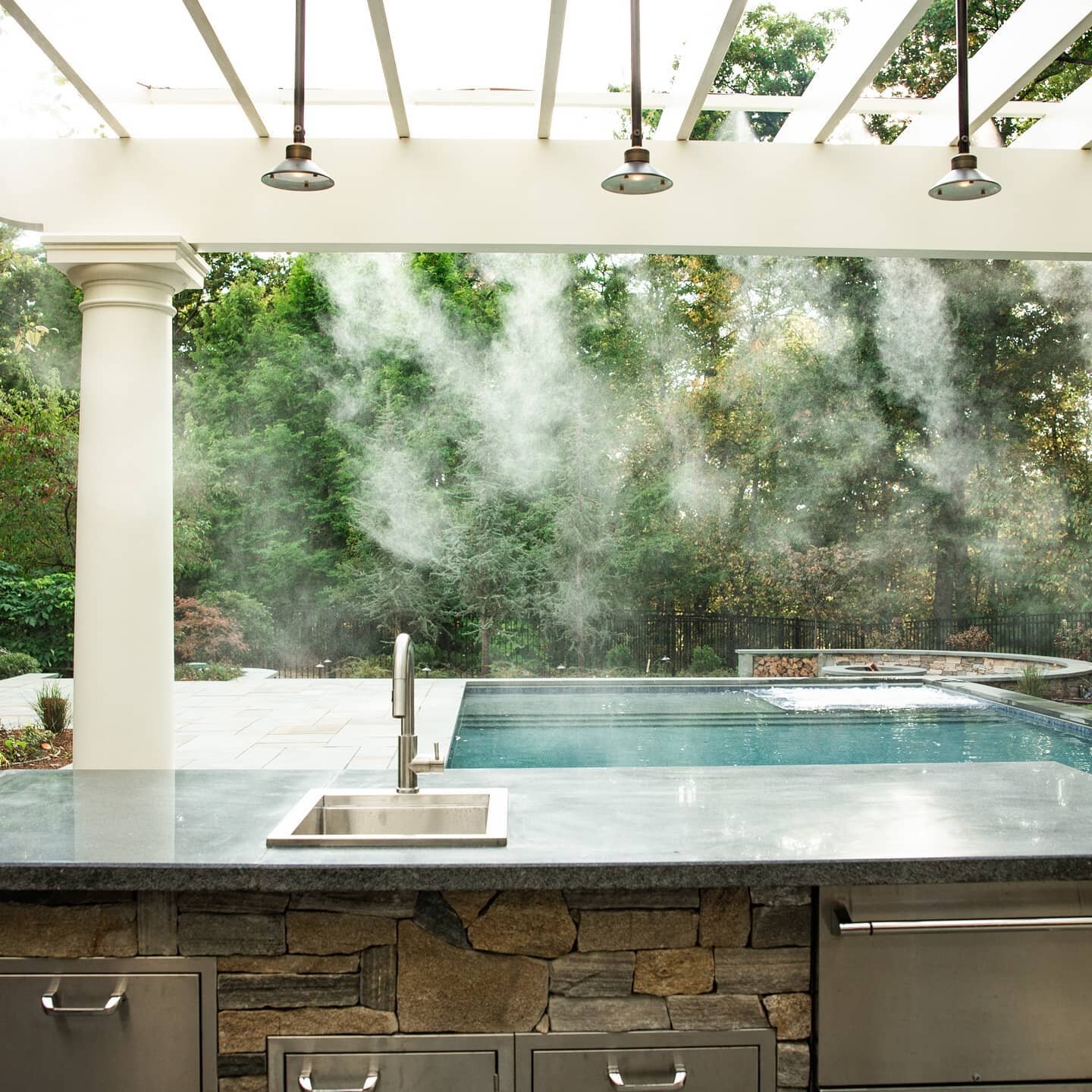 This outdoor kitchen is built for these hot summer days and has a complete line up of Lynx appliances. The overhanging pergola with a built-in misting system provides a break from the sun and humidity. #outdoorliving