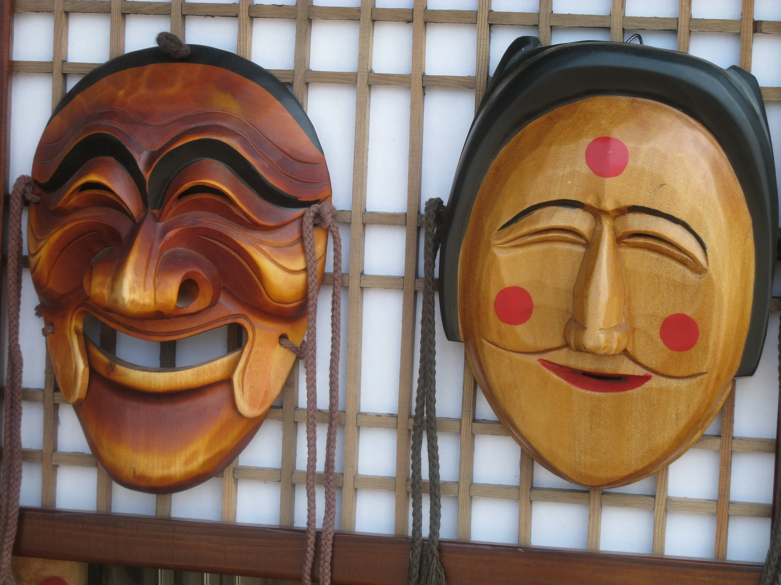 Two Korean Hahoetal masks displaying noticeably different smiles (left: the powerful, domineering aristocrat Yangban; right: the affiliative, flirtatious Pune).