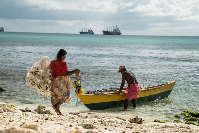 Kiribati locals. A wife helps her husband load up his fishing boat before he departs to the sea.