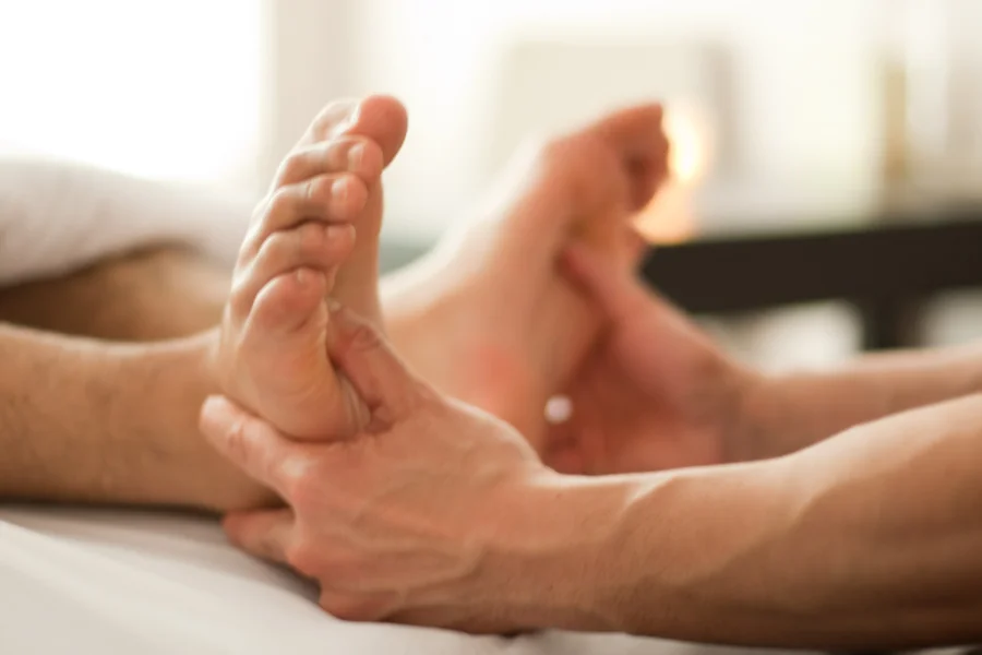 Massage therapist pressing on the solar plexus reflexology points on a client's feet.