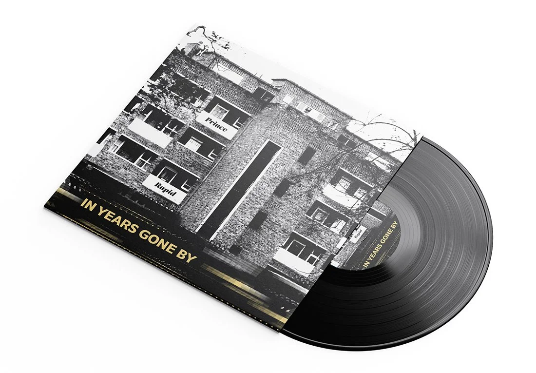 A vinyl record and album cover featuring a black and white photograph of an old brick building with balconies, trees, and the text 'IN YEARS GONE BY'.