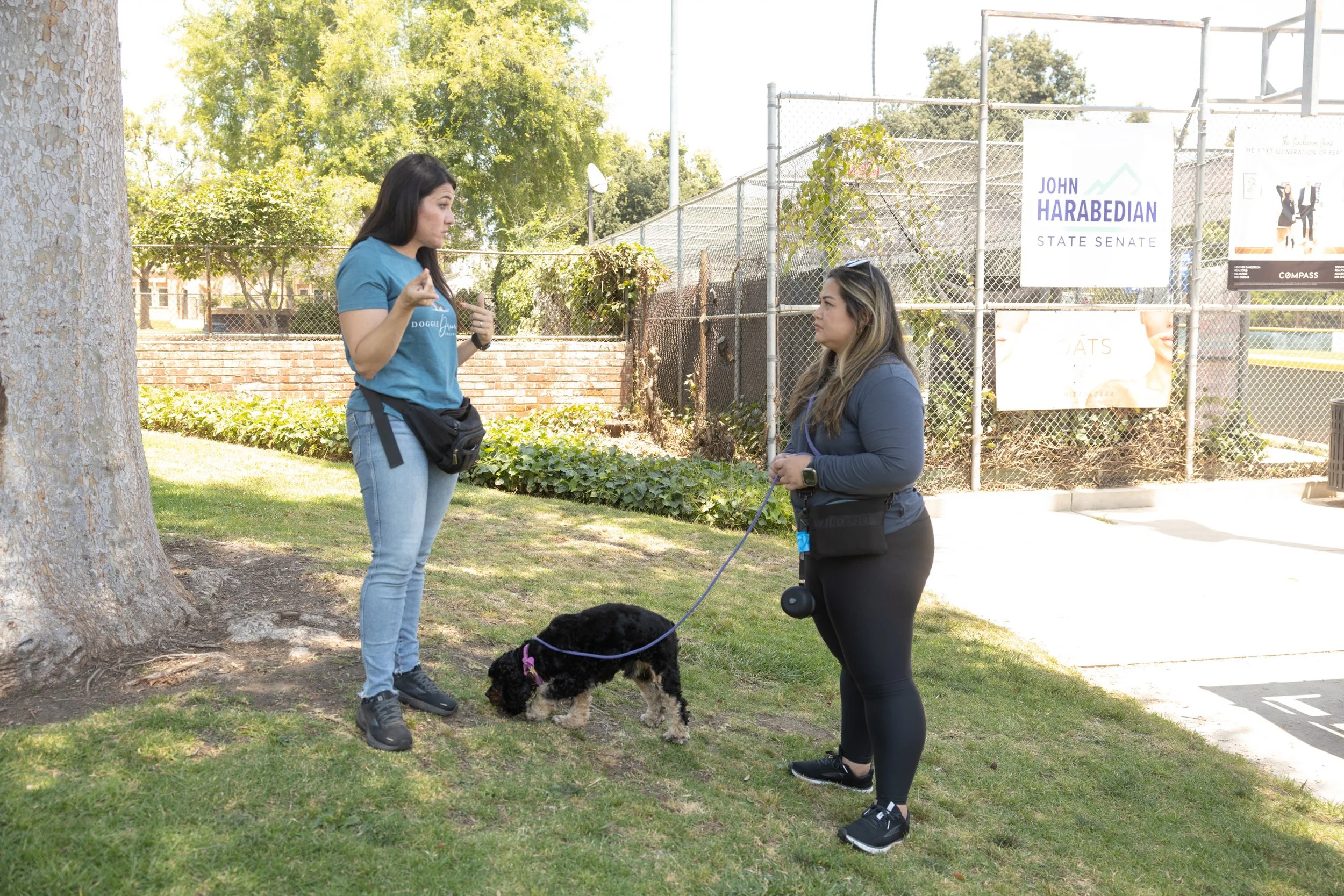 two women talking with dog in the middle on leash