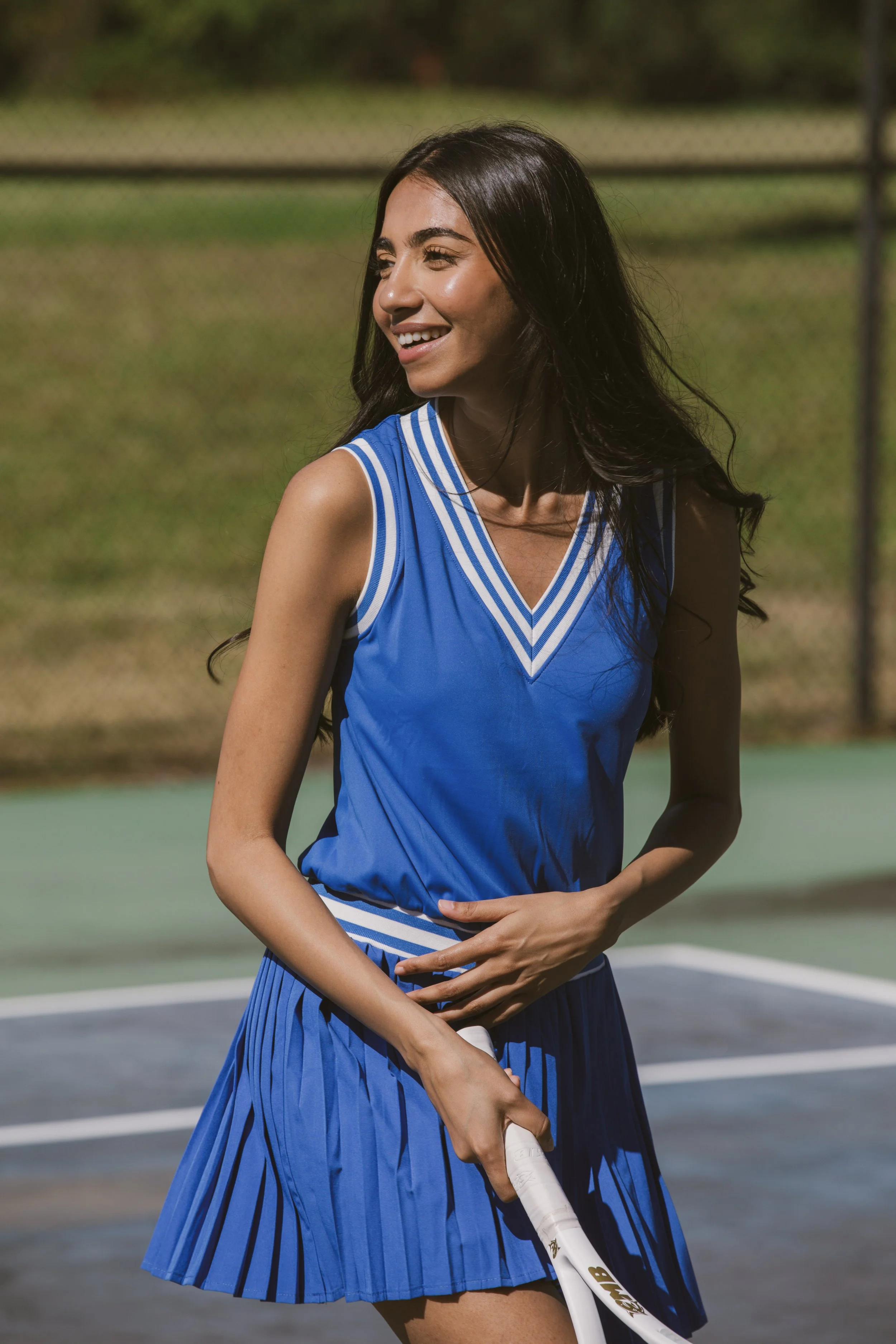 A young woman in a blue sports dress holding a tennis racket on a tennis court.