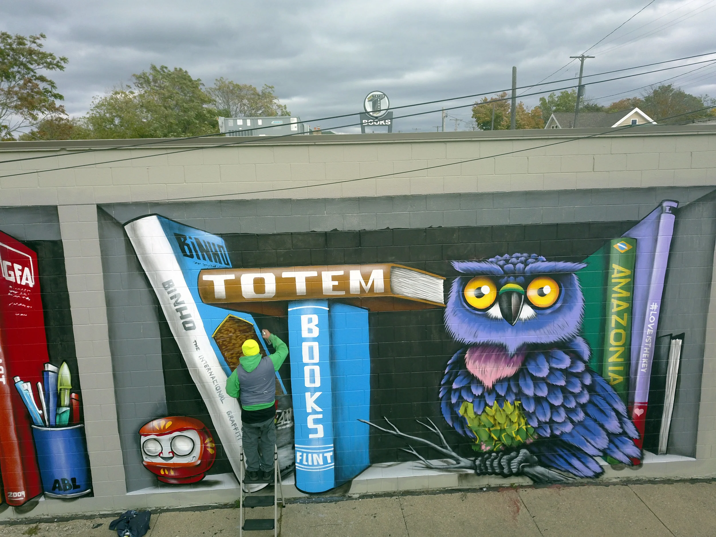 brazilian artist and graffiti legend, binho ribeiro, adds finishing details to his literary themed mural at totem books.