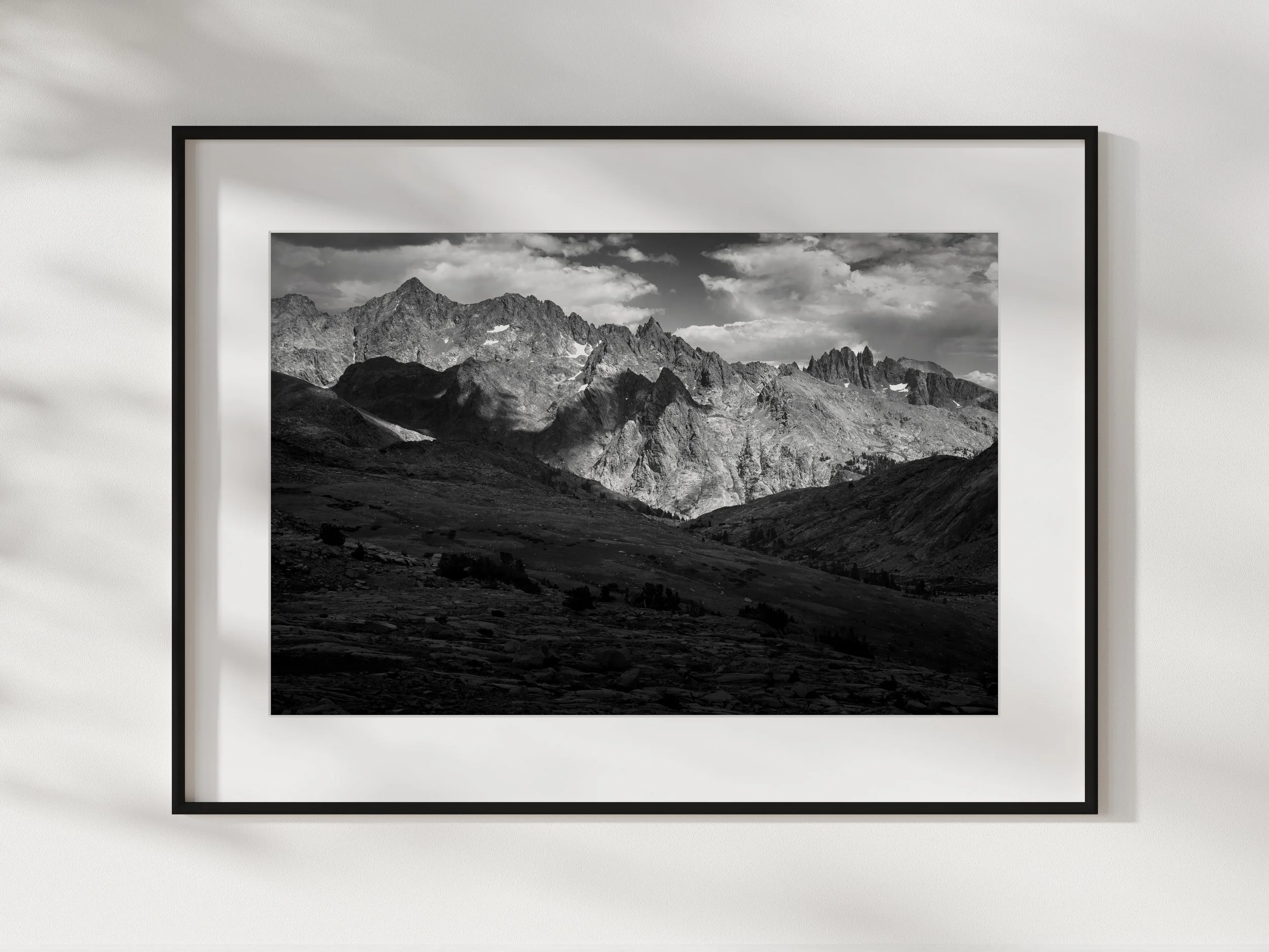 Black and white framed photograph of a mountainous landscape on a white wall.