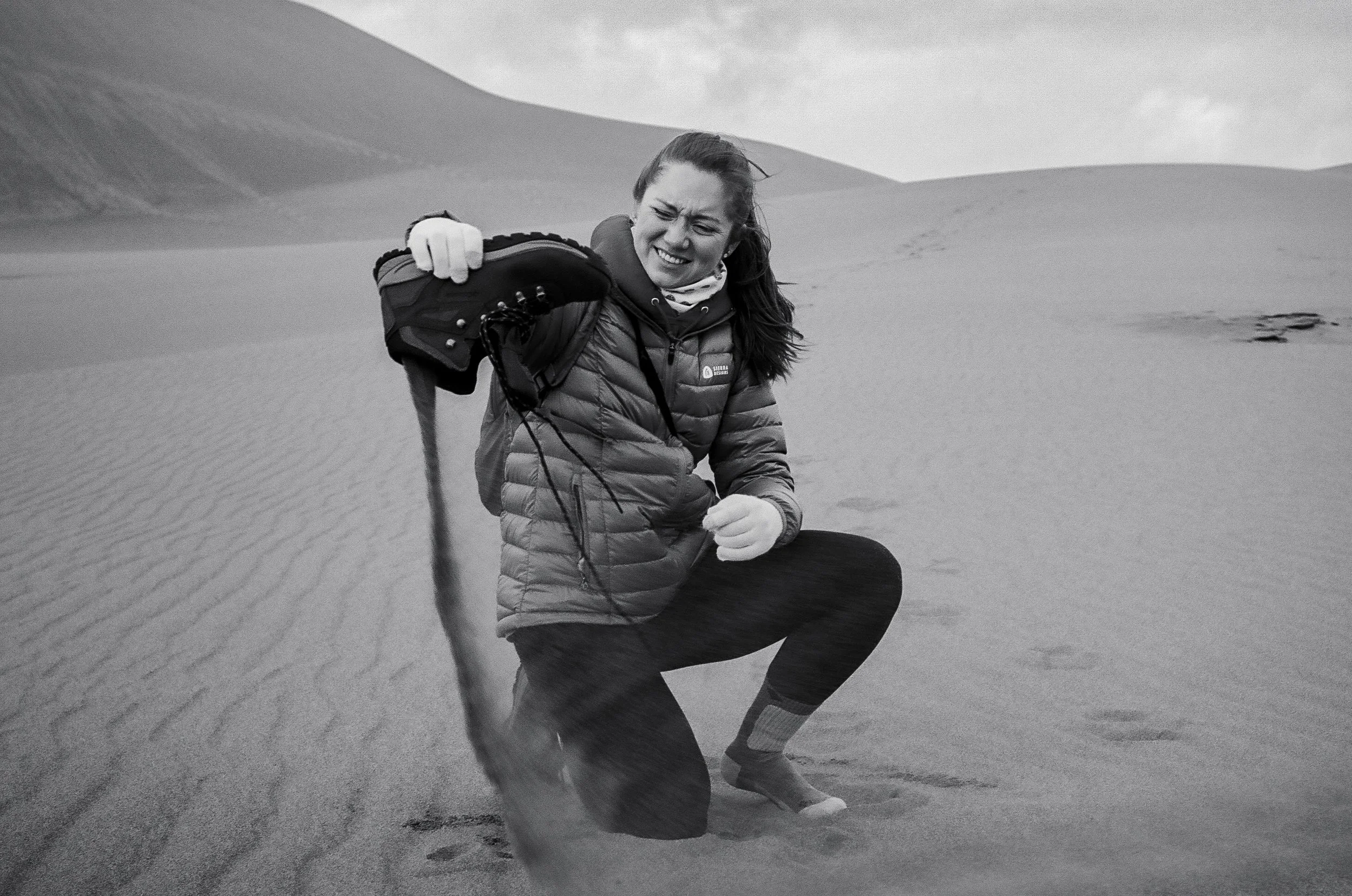 A woman empties sand from her hiking boots at Great Sand Dunes National Park in Colorado