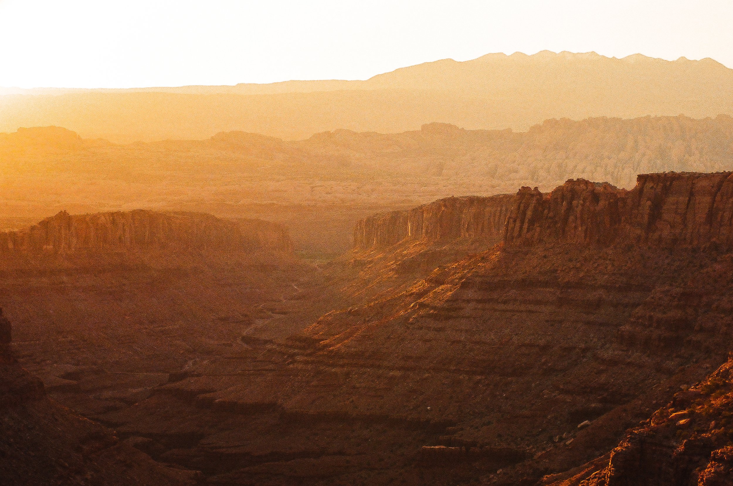 Sunset over the Grand Canyon with layered cliffs and deep valleys in warm orange hues.
