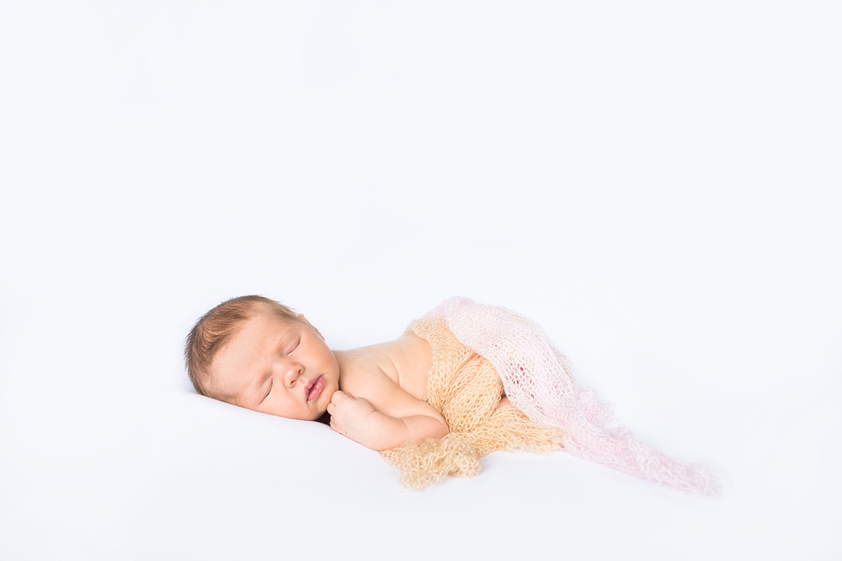  newborn baby posing in a white studio 