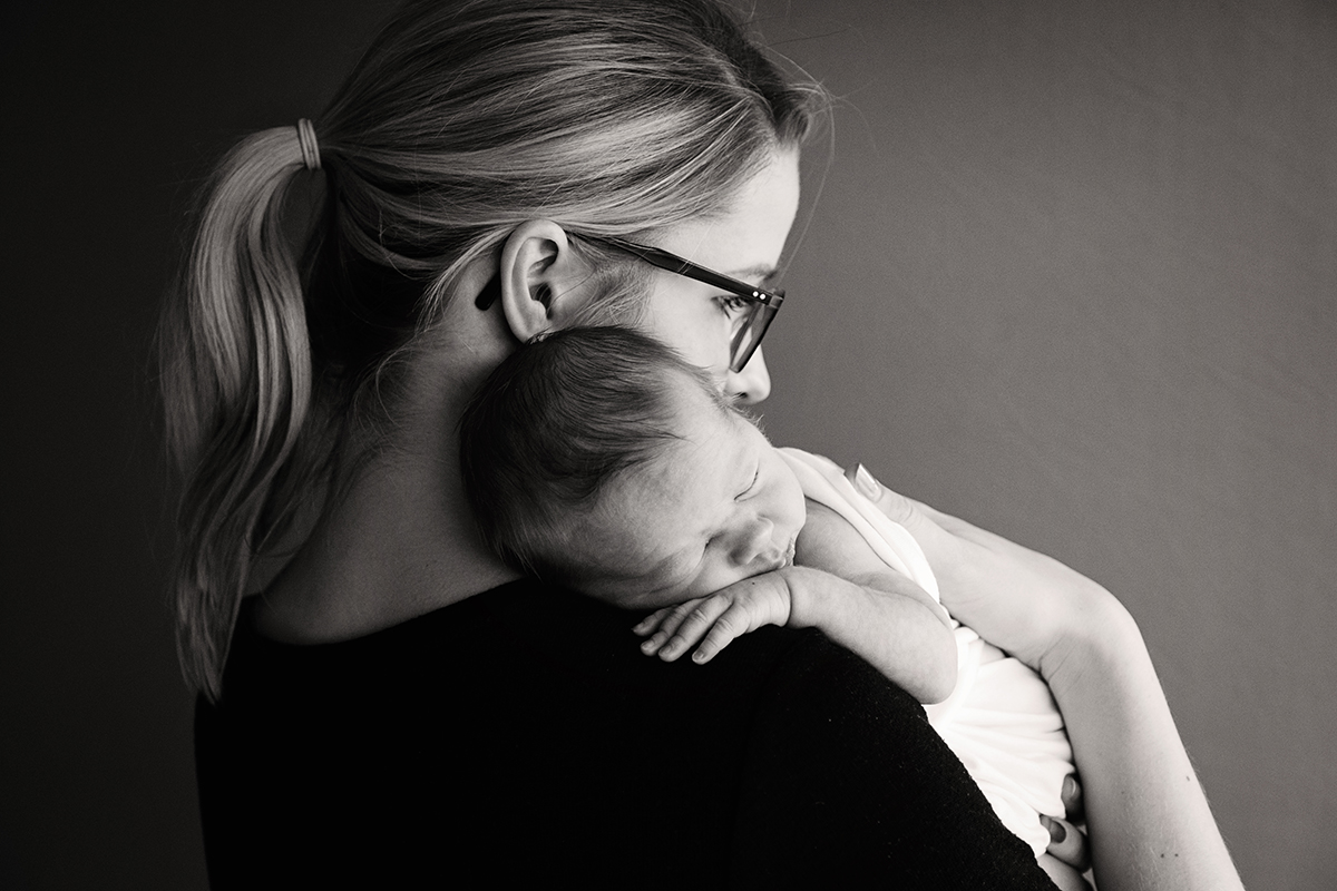  Black and white image of a mum holding her newborn baby on her shoulder 