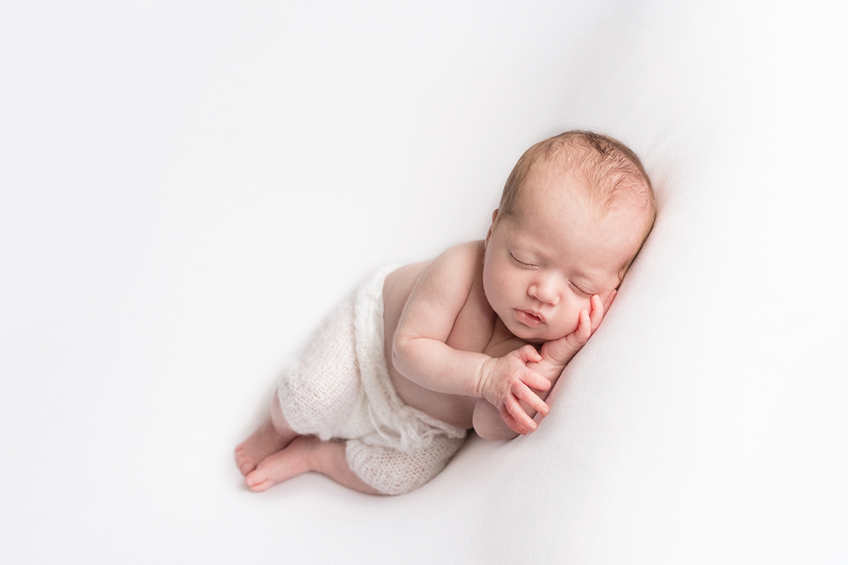  newborn baby girl in white pants sleeping 