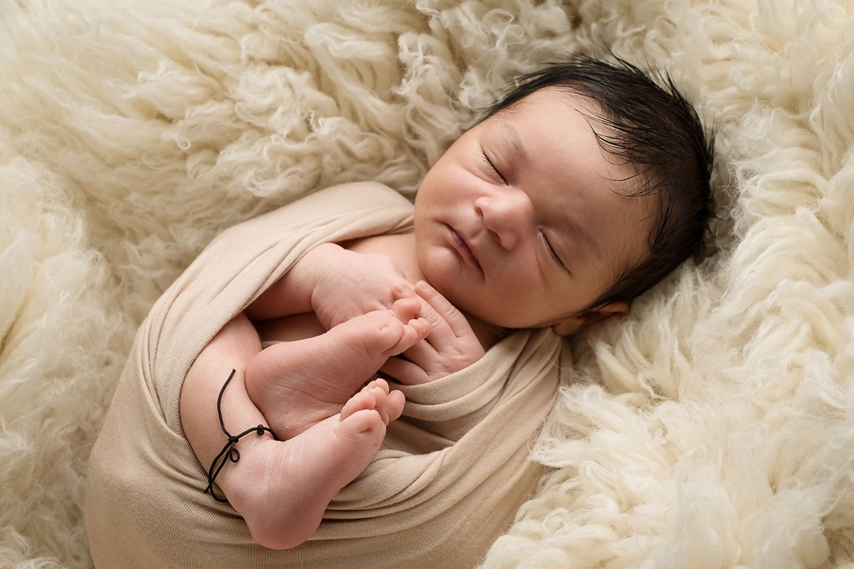 Newborn baby boy sleeping on a rug.jpg