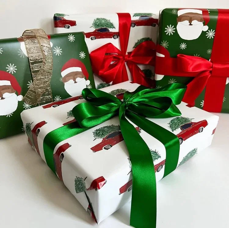 Three wrapped Christmas presents with festive wrapping paper featuring Katsie Klaus and an old-1966 Ford Fairlane with a Christmas tree on its roof, decorated with green and red ribbons, and gold and red bows.
