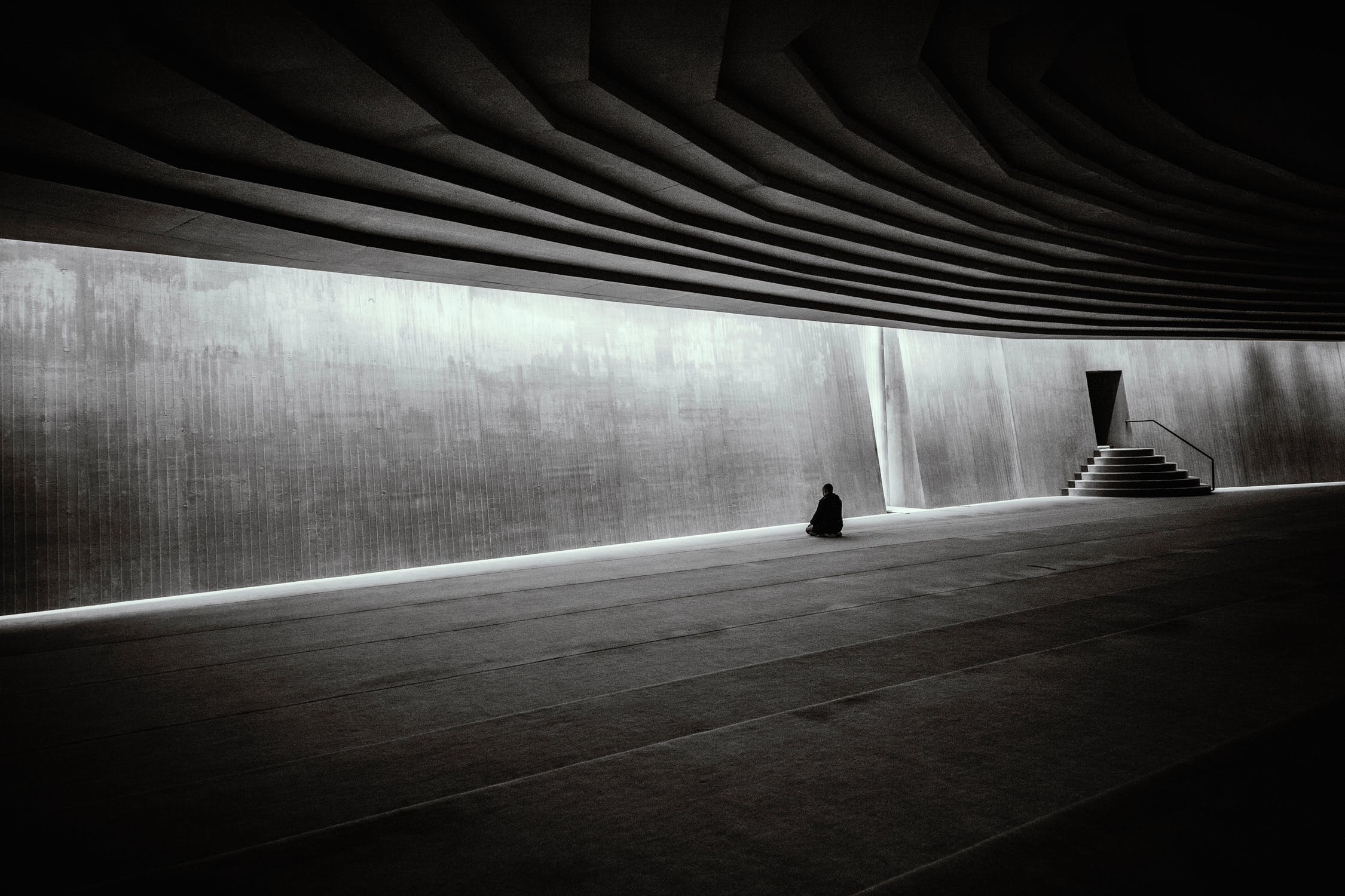 Man meditates in empty hallway